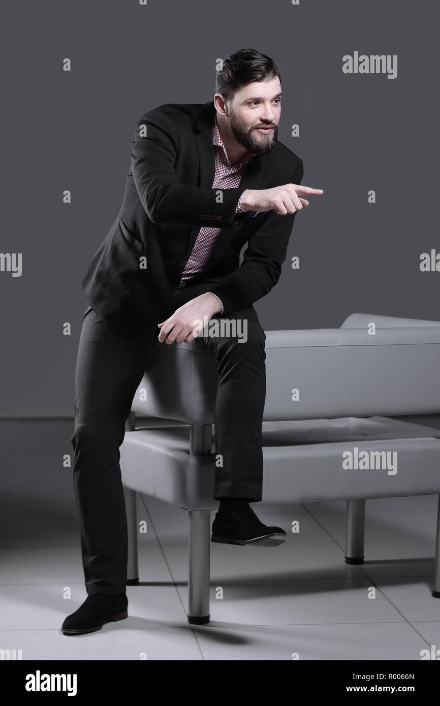 Homme d'affaires moderne assis sur le dos de la chaise et montrant l'avant du doigt Banque D'Images