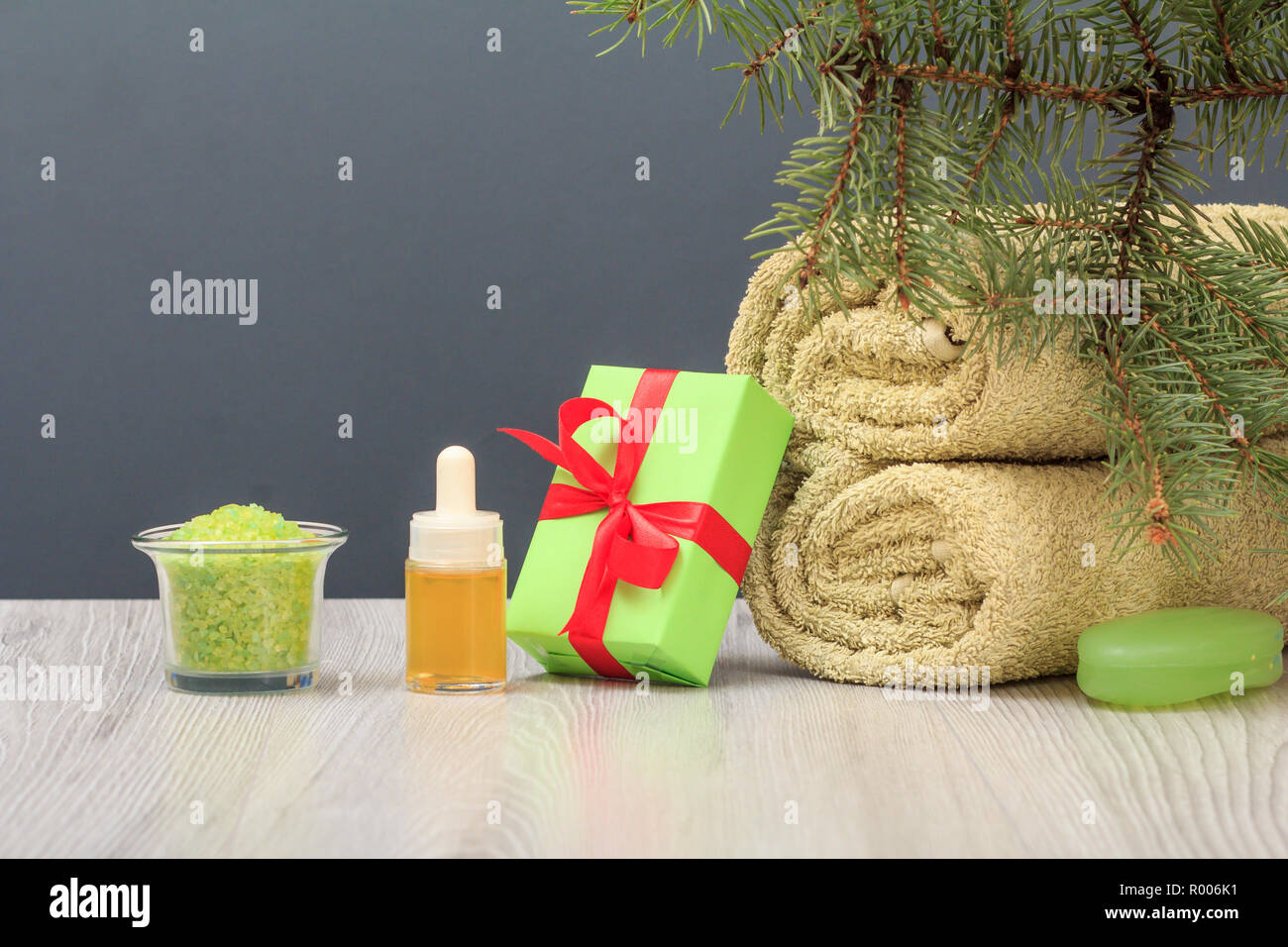 Composition Spa avec une serviette éponge doux, bouteille avec de l'huile aromatique, coffret-cadeau, d'un bol avec du sel de mer, du savon et de l'arbre branche de sapin sur fond gris Banque D'Images