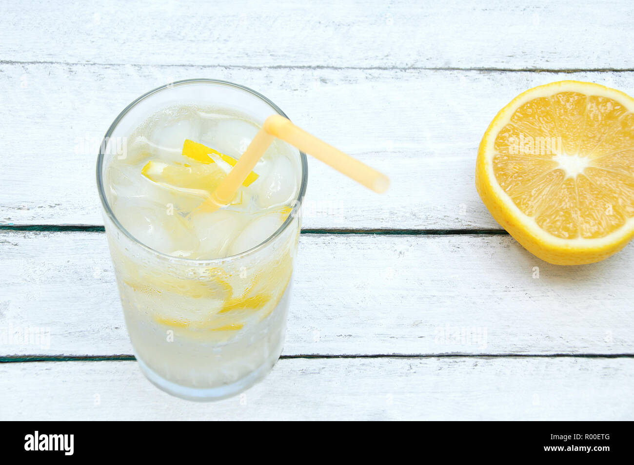 Verre en sueur avec un cocktail avec de la glace et de citron. Sur un fond de bois. Close-up. Banque D'Images