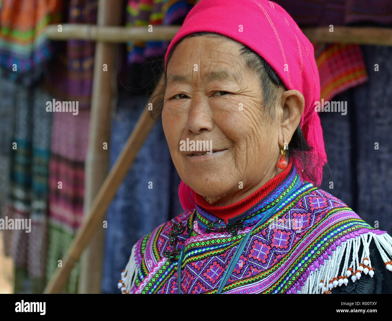Personnes âgées H'Mong fleurs vietnamiennes hill-tribu femme porte fleur brodée tenue H'Mong et un foulard rose. Banque D'Images