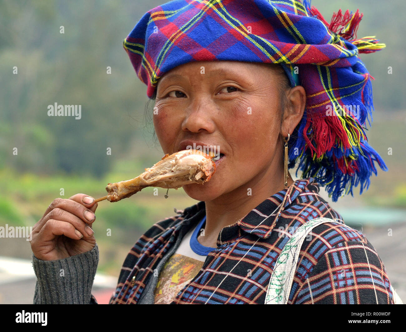 Des minorités ethniques vietnamiennes hill-tribu femme avec la dent d'or mange un wok de poulet pilon. Banque D'Images