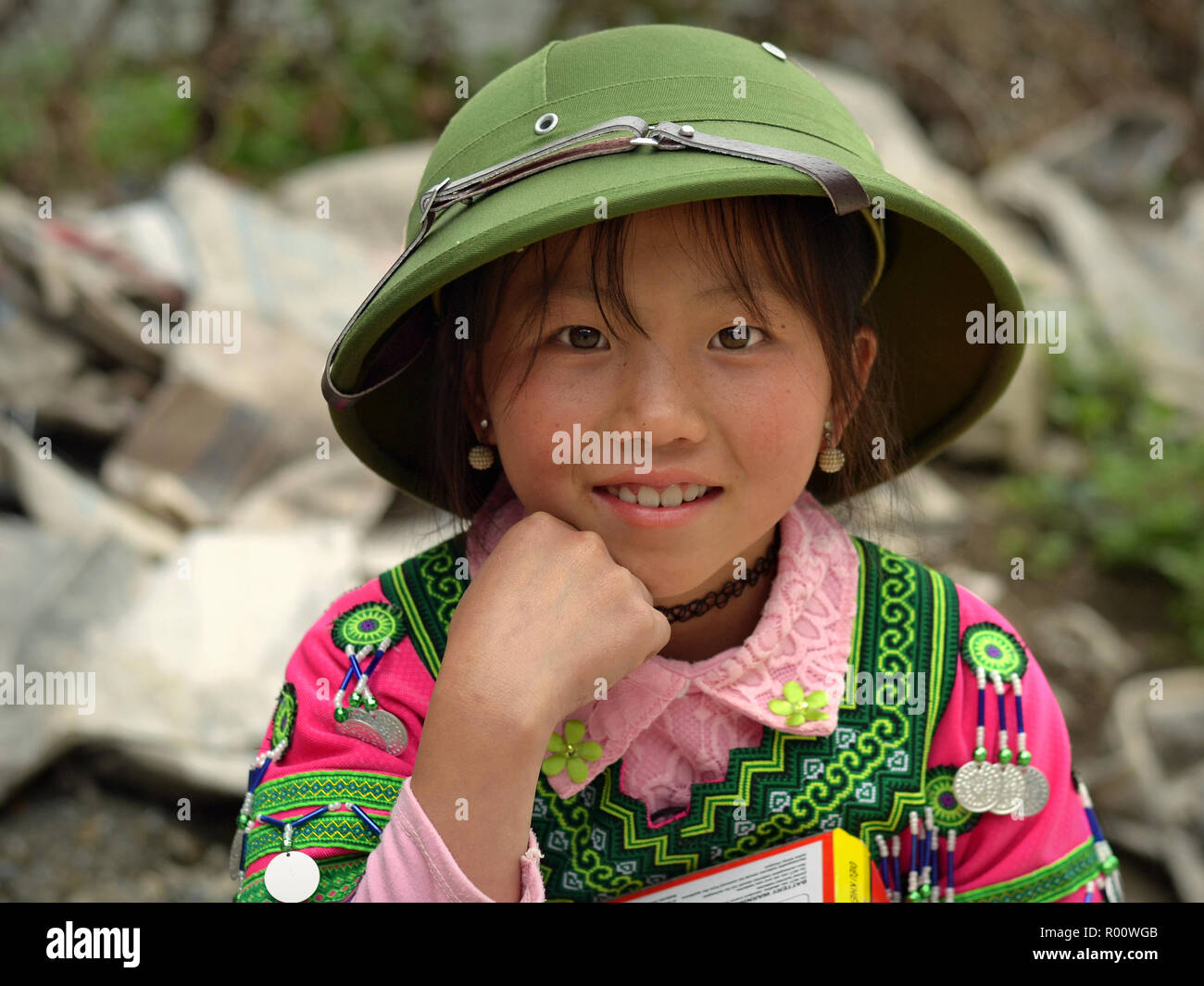 Cute H'Mong vietnamienne des minorités ethniques-hill-tribu preteen girl avec une tenue tribale traditionnelle et d'un tout nouveau casque colonial de l'armée du Nord Vietnam. Banque D'Images