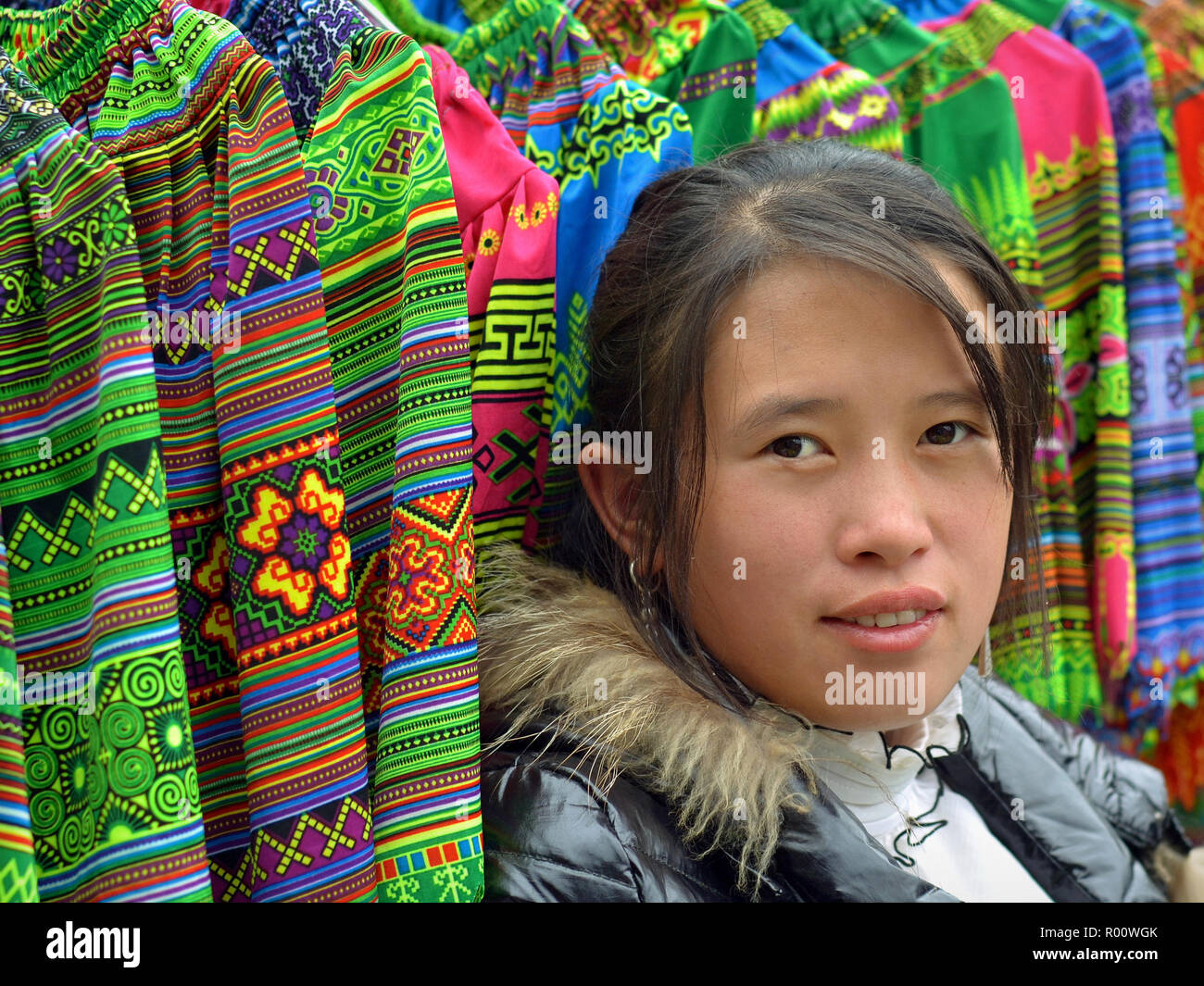 Jeunes vietnamiens H'Mong et les minorités ethniques hill-tribu vendeuse pose pour la caméra en face d'elle des marchandises (jupes). traditionnels brodés Banque D'Images