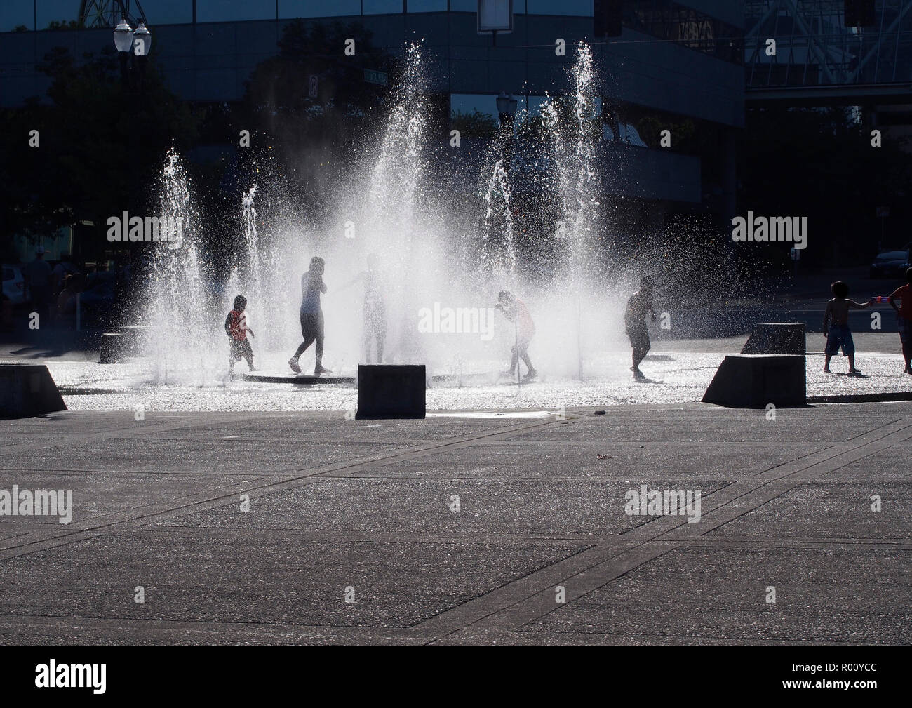 Enfants jouant dans une fontaine sur une chaude journée Banque D'Images