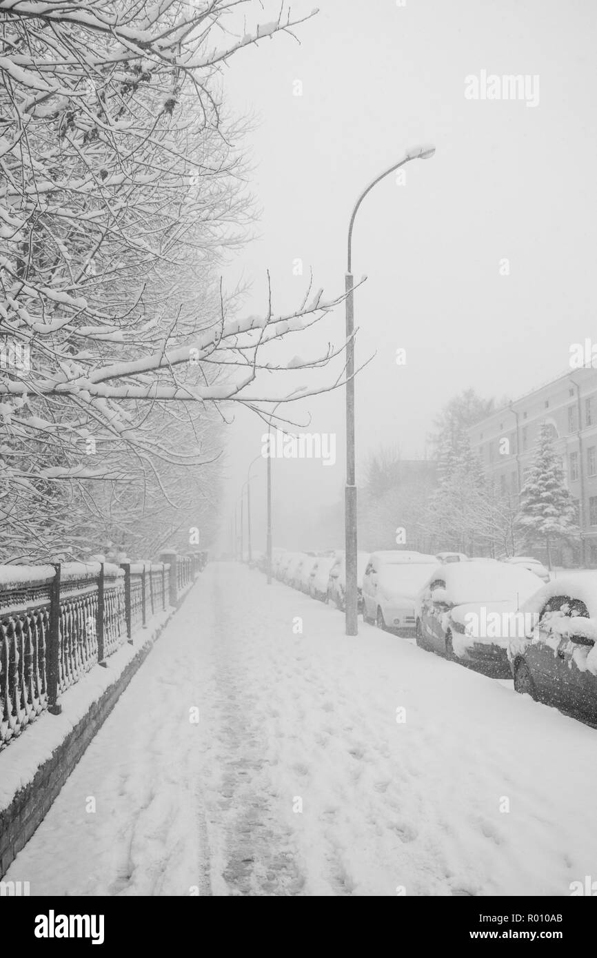 Les trottoirs couverts de neige et des voitures en stationnement le long de celui-ci lors de fortes chutes de neige. Banque D'Images