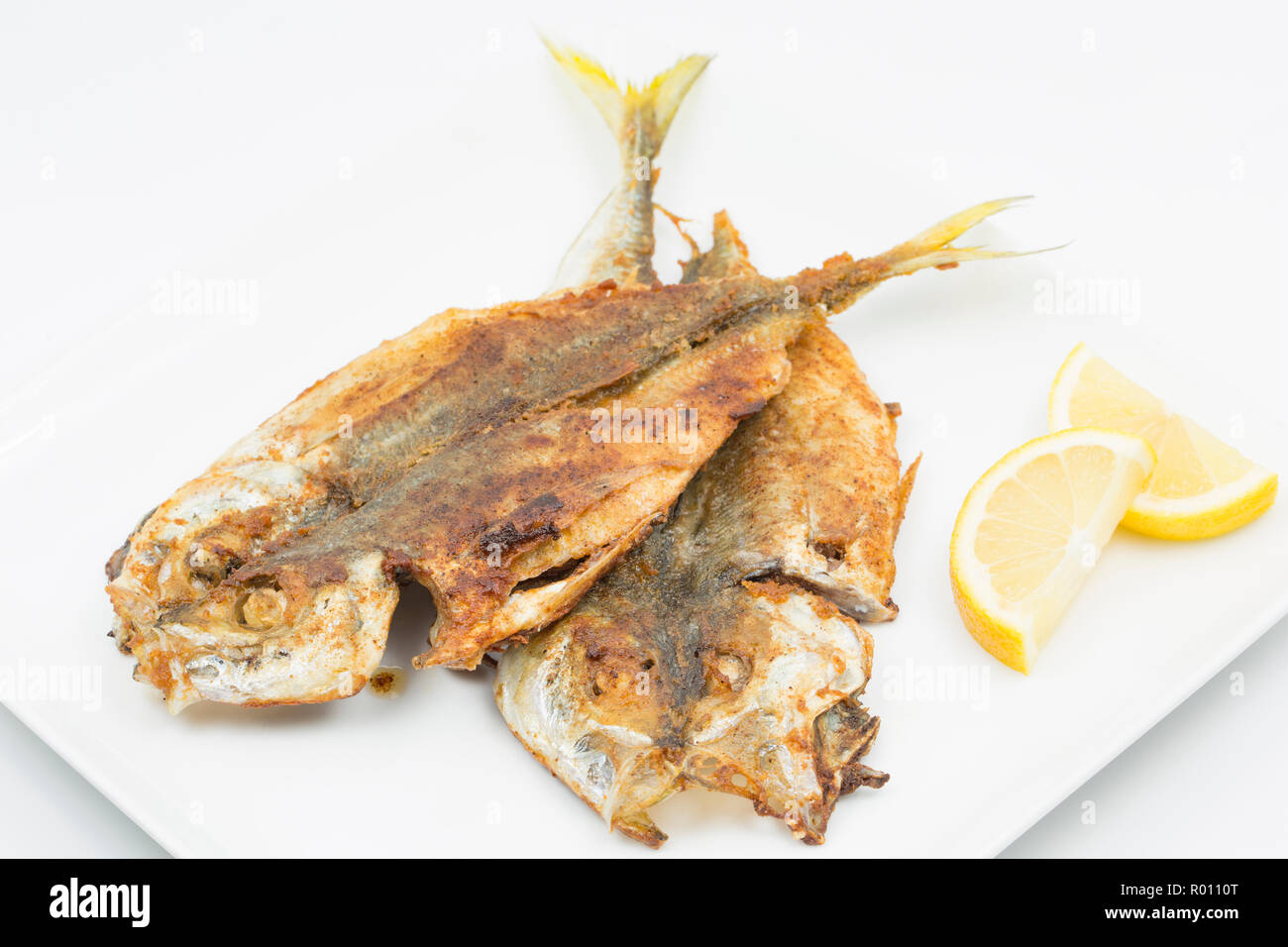 Une paire de Scad faits maison, ou Chinchard Trachurus trachurus,, qui ont été déchirés, trempé dans de la farine assaisonnée avec le cumin et le paprika et frits sur Banque D'Images