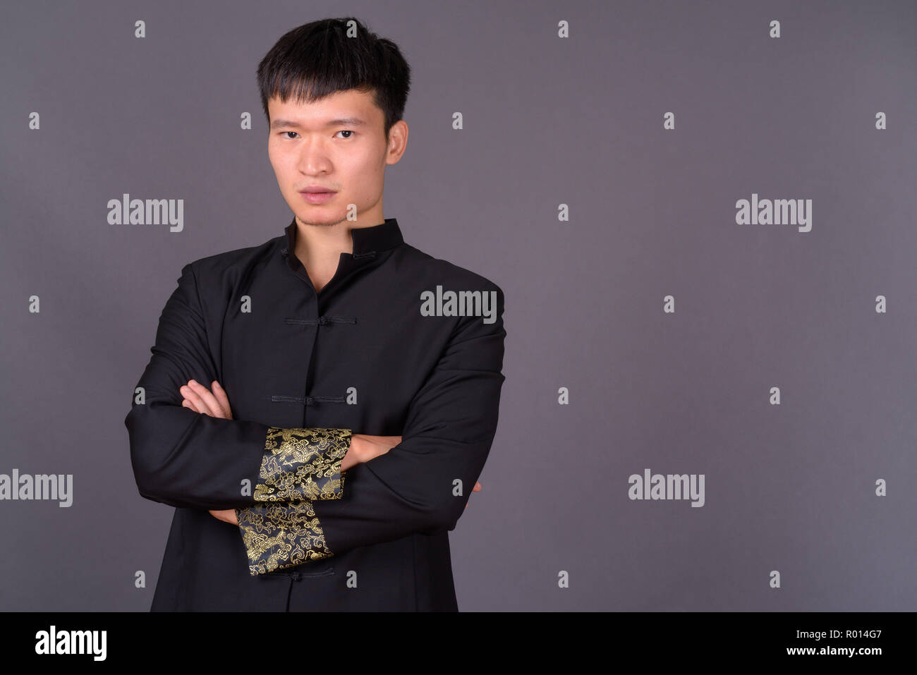 Portrait de jeune homme d'origine chinoise contre l'arrière-plan gris Banque D'Images