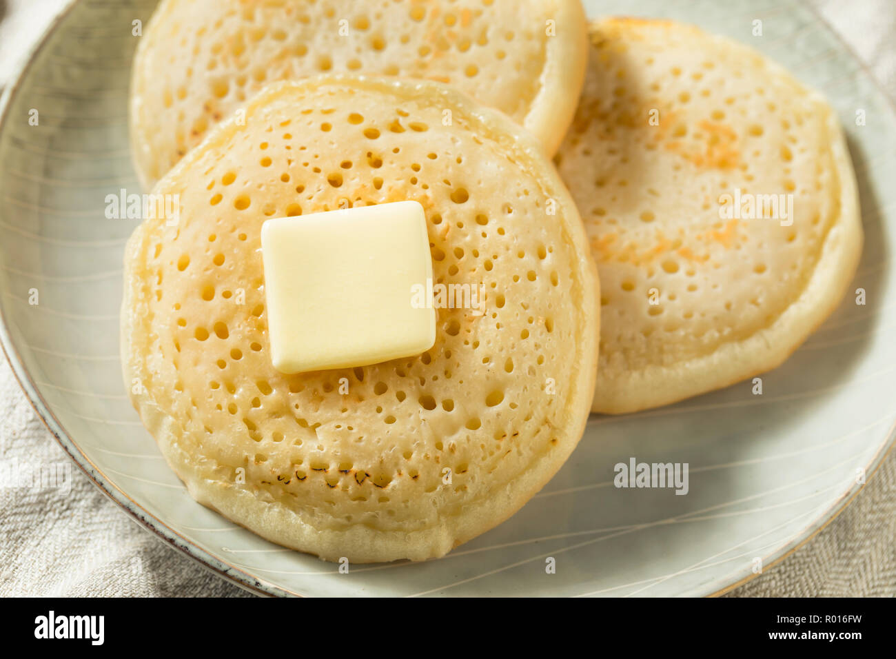 Des Crumpets britannique grillé avec du beurre pour le petit déjeuner Banque D'Images