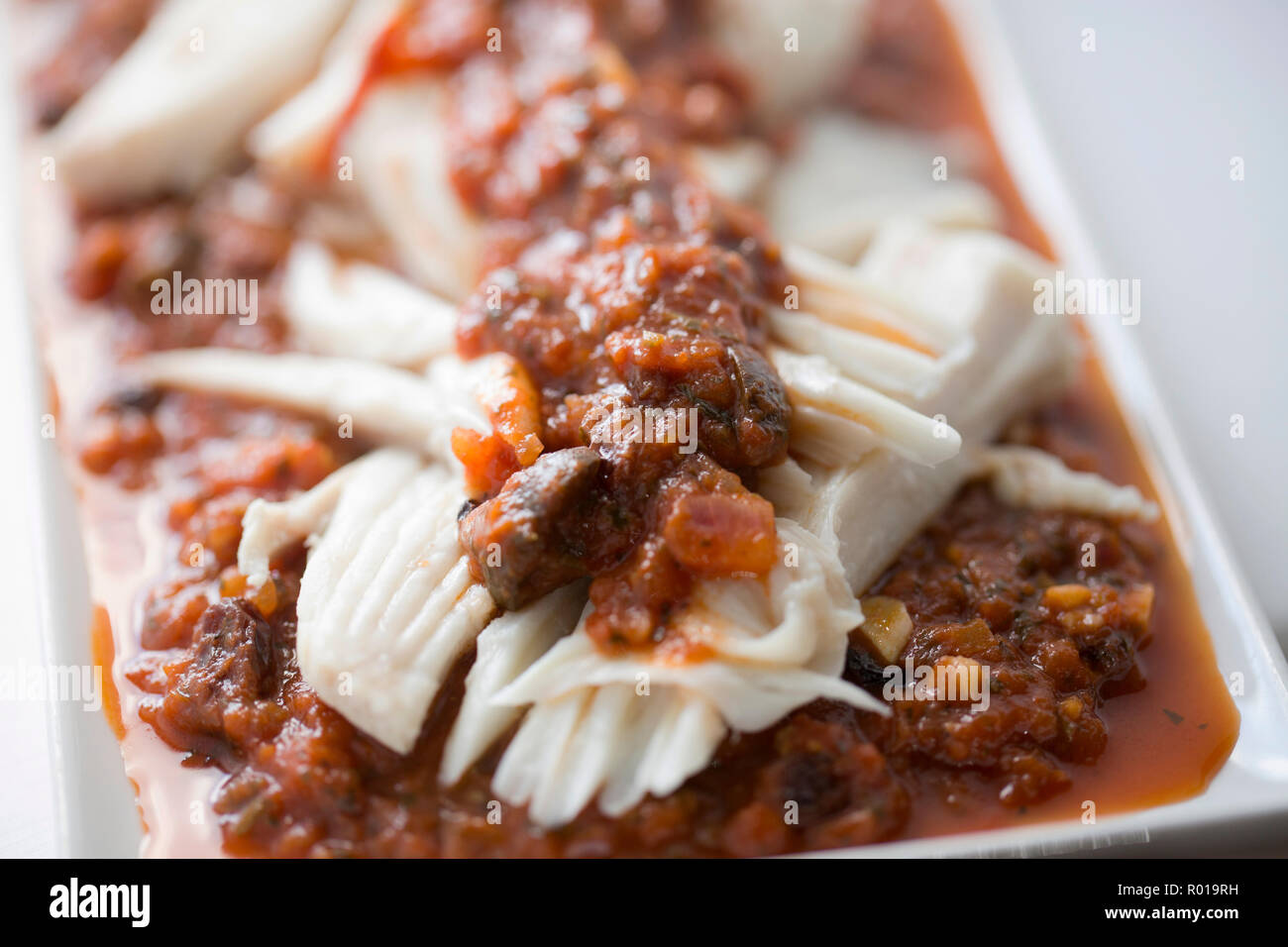 Accueil plats ray ailes d'une ray pris dans la Manche qui ont été mitonnées, avait le cartilage retiré, puis servi avec une sauce tomate Banque D'Images