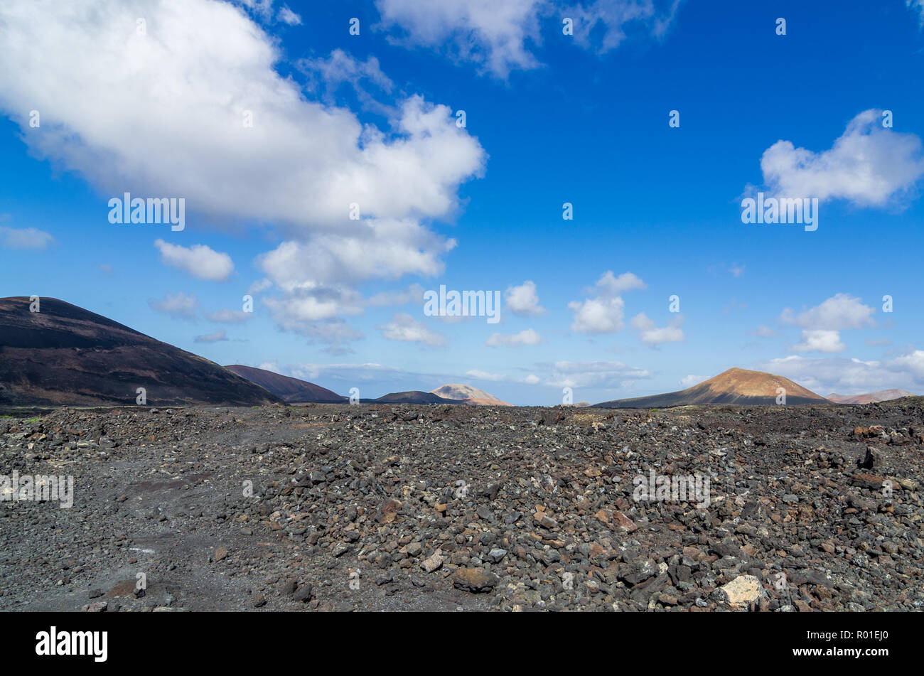 Vue sur un champ de lave sur Lanzarote avec les volcans en arrière-plan, îles Canaries, Espagne Banque D'Images