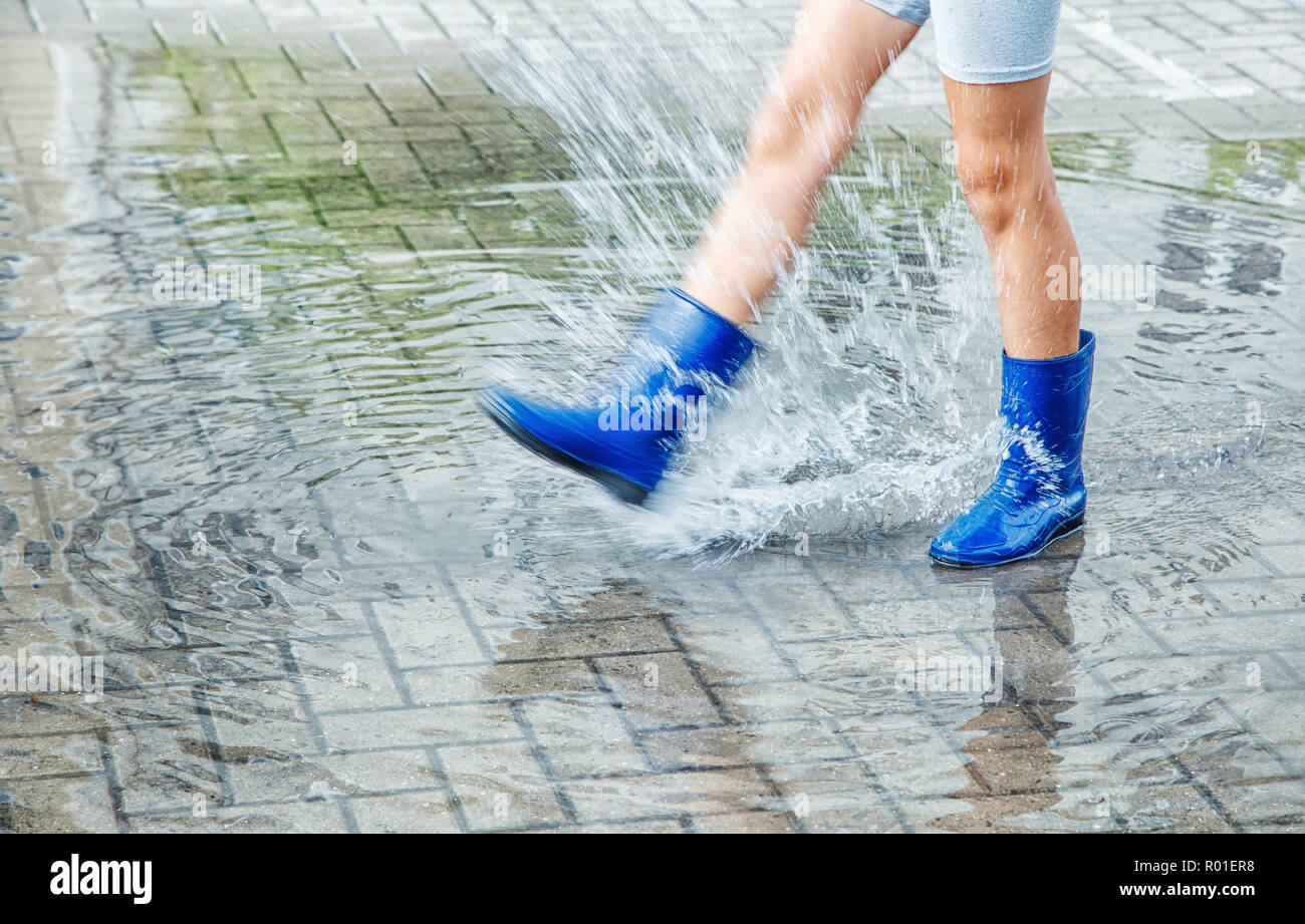 Fille en bleu bottes de caoutchouc qui saute dans une flaque d'eau après  une pluie outdoor le jour d'été. jambes libre Photo Stock - Alamy
