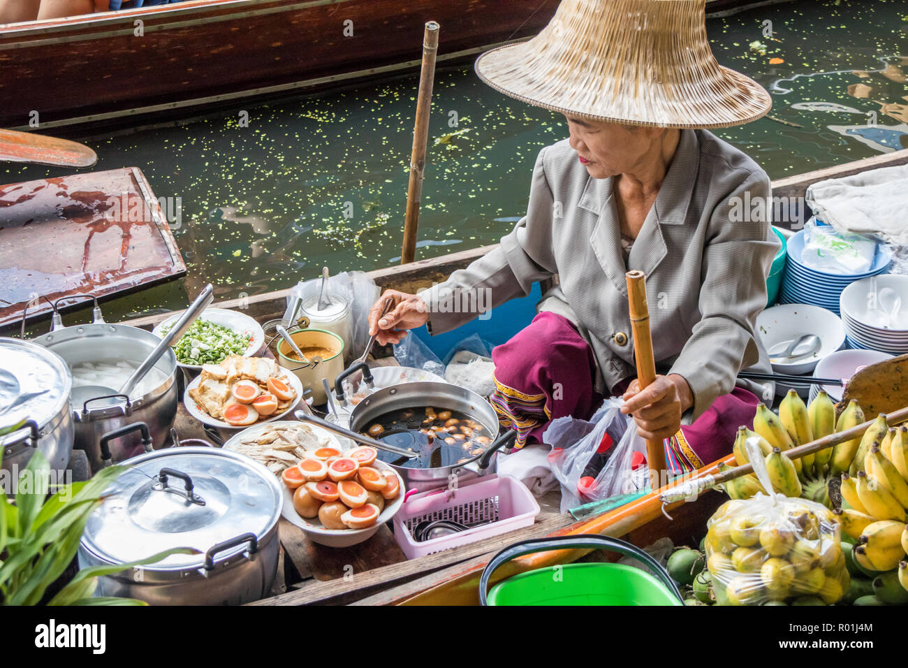 Damnoen Saduak, Thaïlande - 8 octobre 2018 : vendeur femme la préparation des aliments au marché flottant. Le marché est une destination touristique très poular. Banque D'Images