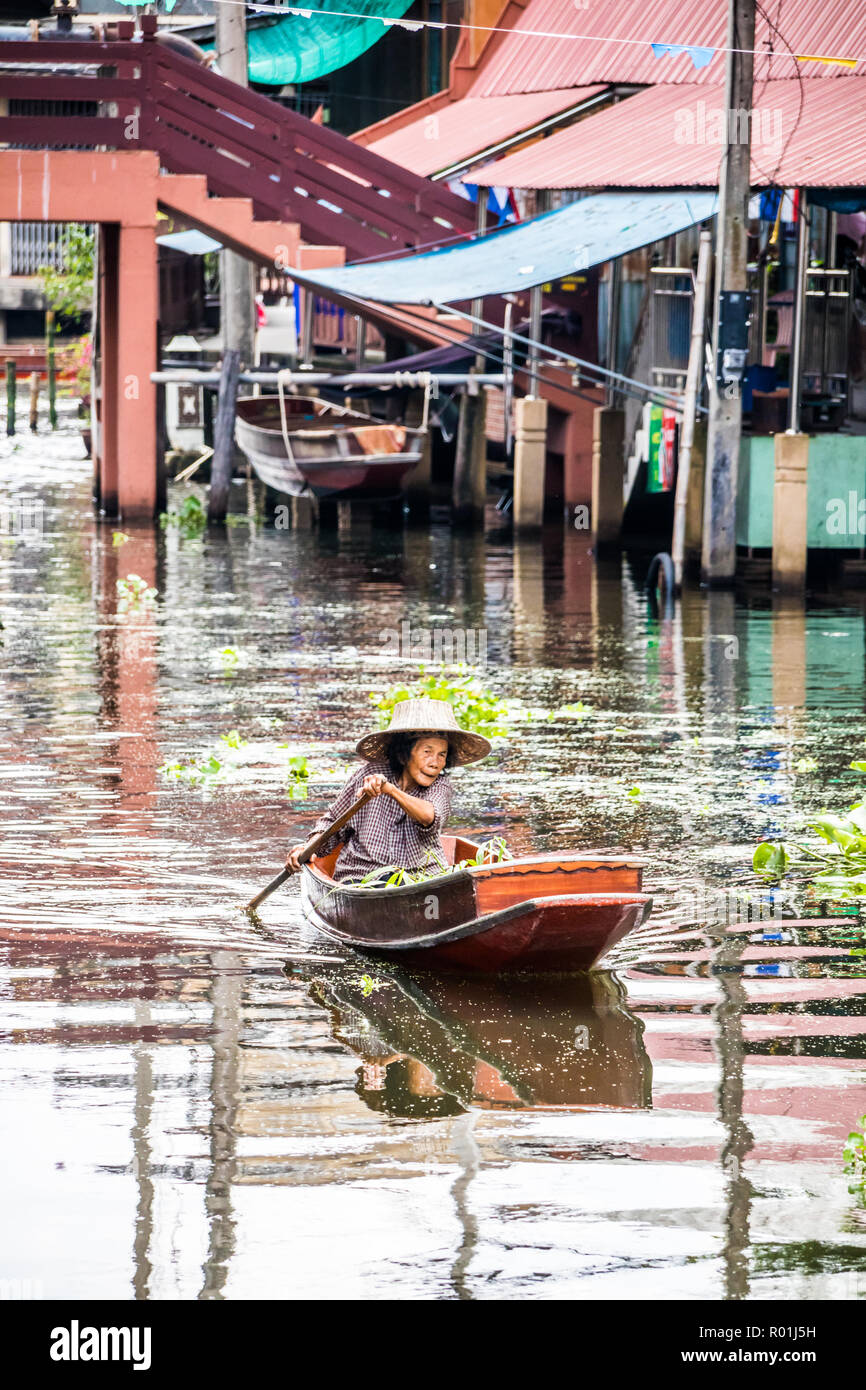 Damnoen Saduak, Thaïlande - 8 octobre 2018 : une femme paddles son bateau le long du canal. Le marché flottant ici est une destination touristique très populaire. Banque D'Images