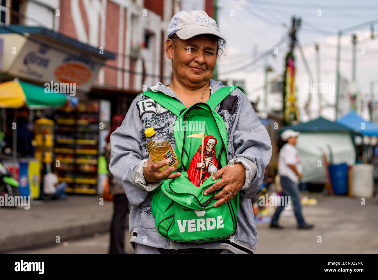 31 octobre 2018, Mexico, Mexico : un disciple de Santa Muerte porte une figure du saint patron dans son sac à dos au lieu de culte dans le quartier de Tepito. Dans sa main elle tient une bouteille avec la liqueur d'agave Mezcal, avec laquelle les statues sont versée au-dessus. Dans la ville de Mexico, des centaines de partisans faisaient des offrandes au saint patron Santa Muerte à l'occasion de la 'Día de los Muertos' ('Day of the Dead'). Les personnes se sont rassemblées le mercredi 31.10.2018 au culte des saints dans le quartier de Tepito. Santa Muerte - en allemand 'holy death' - est représentée par un squelette portant des blouses ou wo Banque D'Images