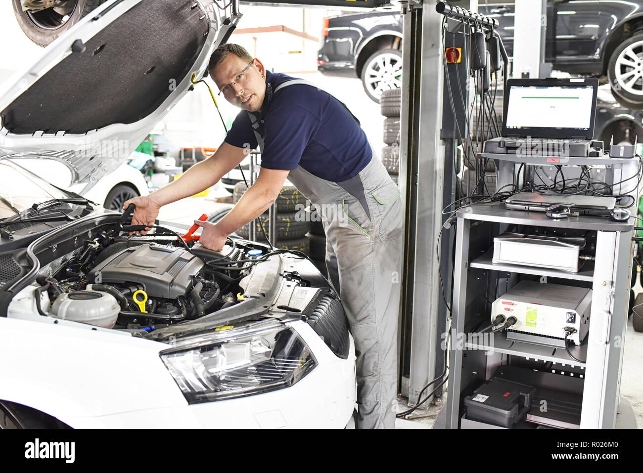 Mécanicien de voiture chargement de la batterie du véhicule dans l'atelier Banque D'Images