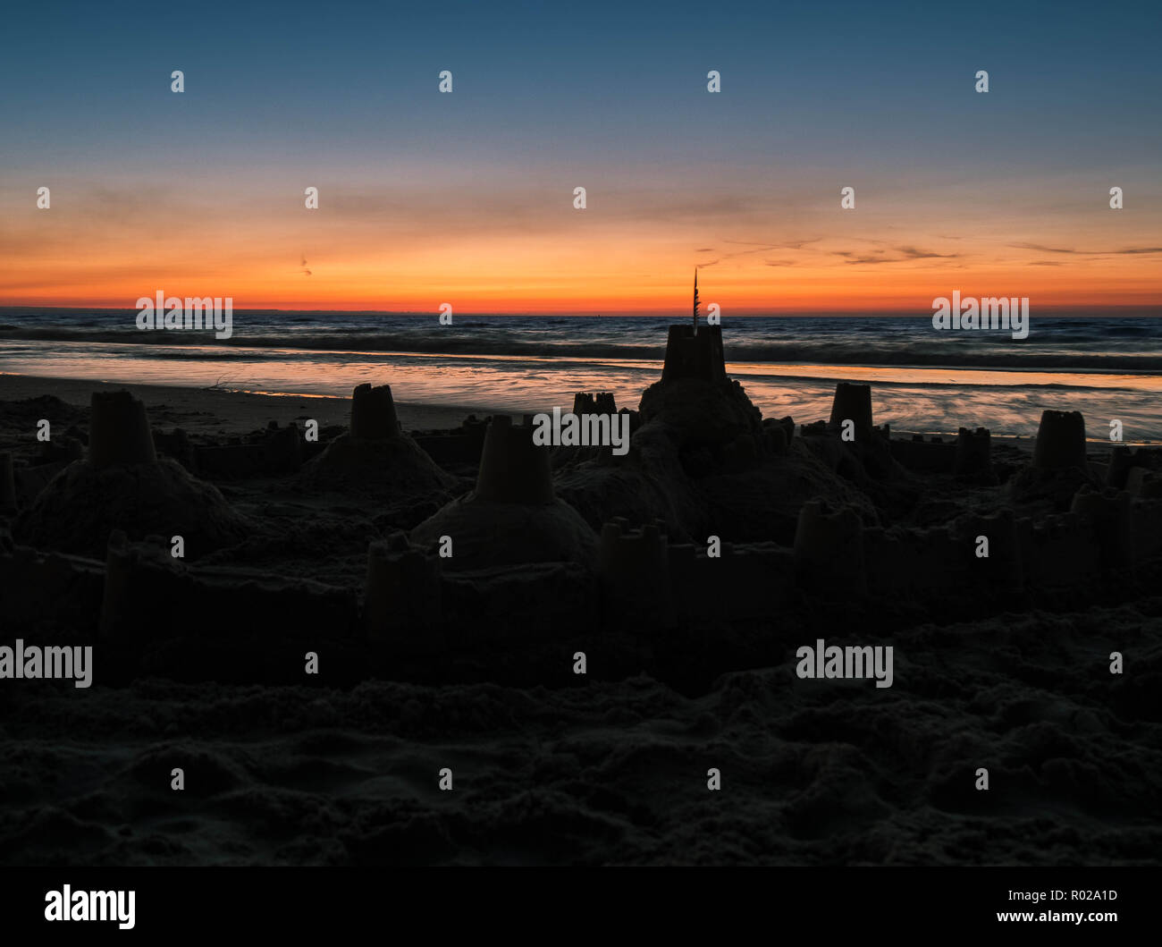 Silhouette d'un château de sable sur la ligne de flottaison après le coucher du soleil Banque D'Images