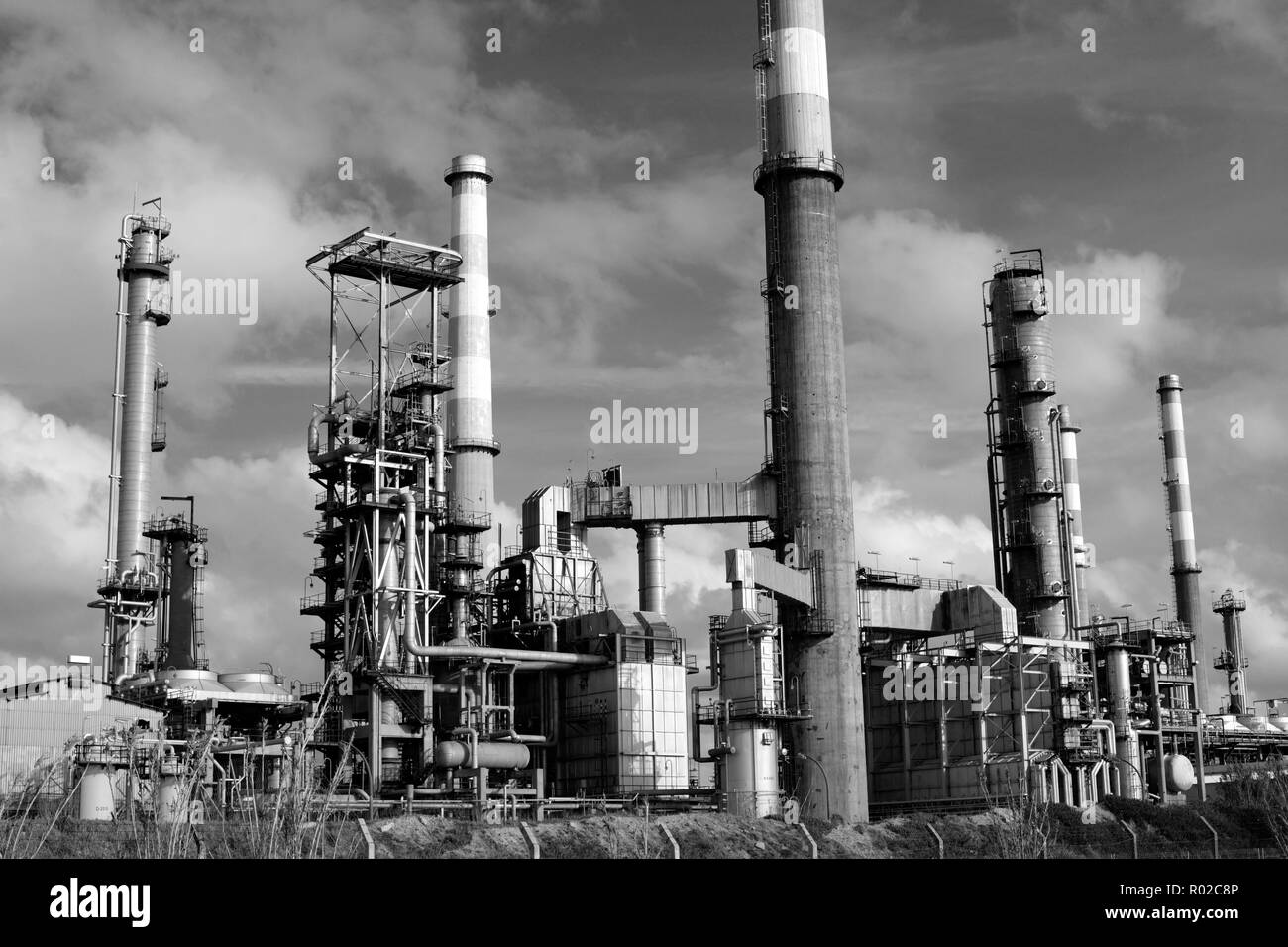 Partie d'une grande raffinerie de pétrole avec beaucoup d'une cheminée en fin d'après-midi nuageux - converties en noir et blanc Banque D'Images