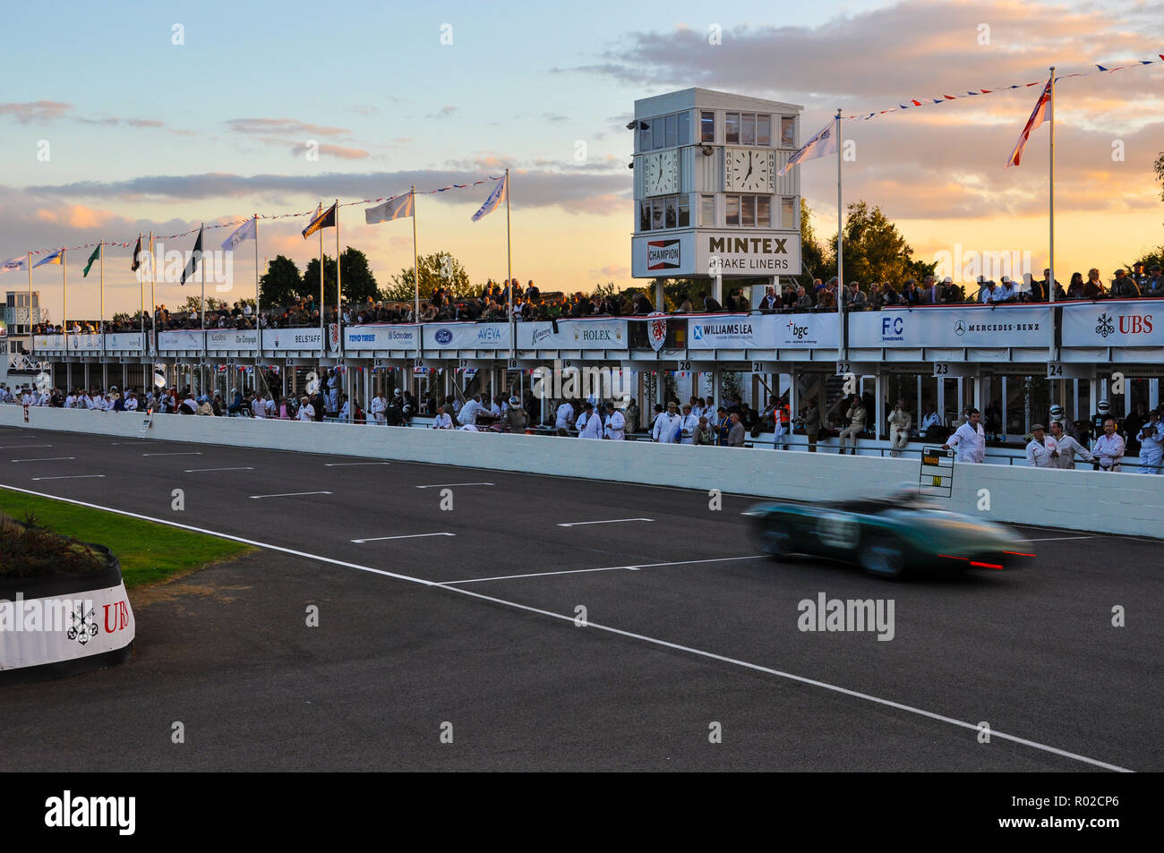 Sunset soir crépuscule course automobile vintage au Goodwood Revival. Course de voiture d'endurance. Voitures de course en ligne droite, stands droit Banque D'Images