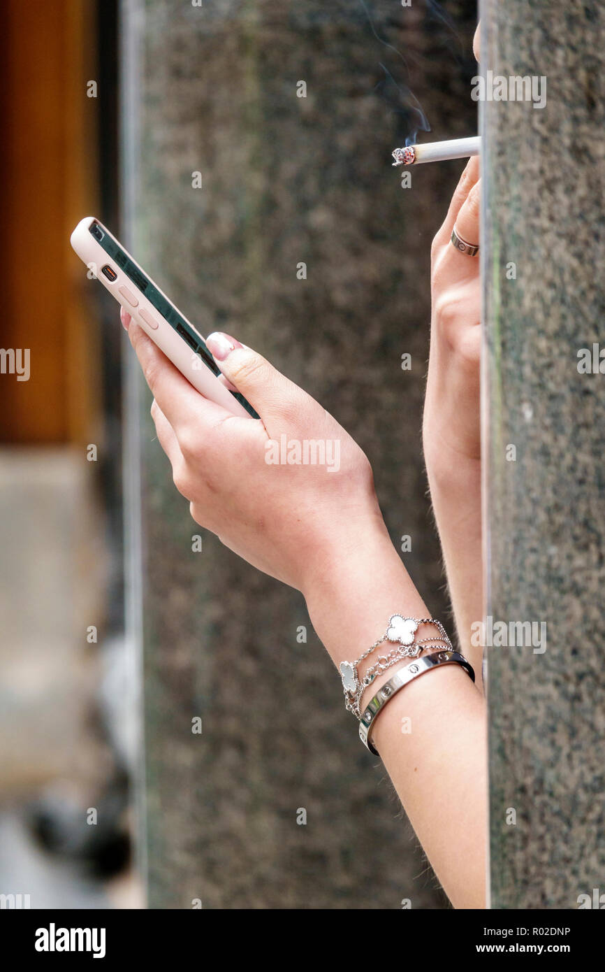 Londres Angleterre,Royaume-Uni,Mayfair,cigarette,fumée de cigarette,trottoir extérieur,mains de femme,utilisation de smartphone,addiction à la nicotine,puffing,vérification de la lecture Banque D'Images