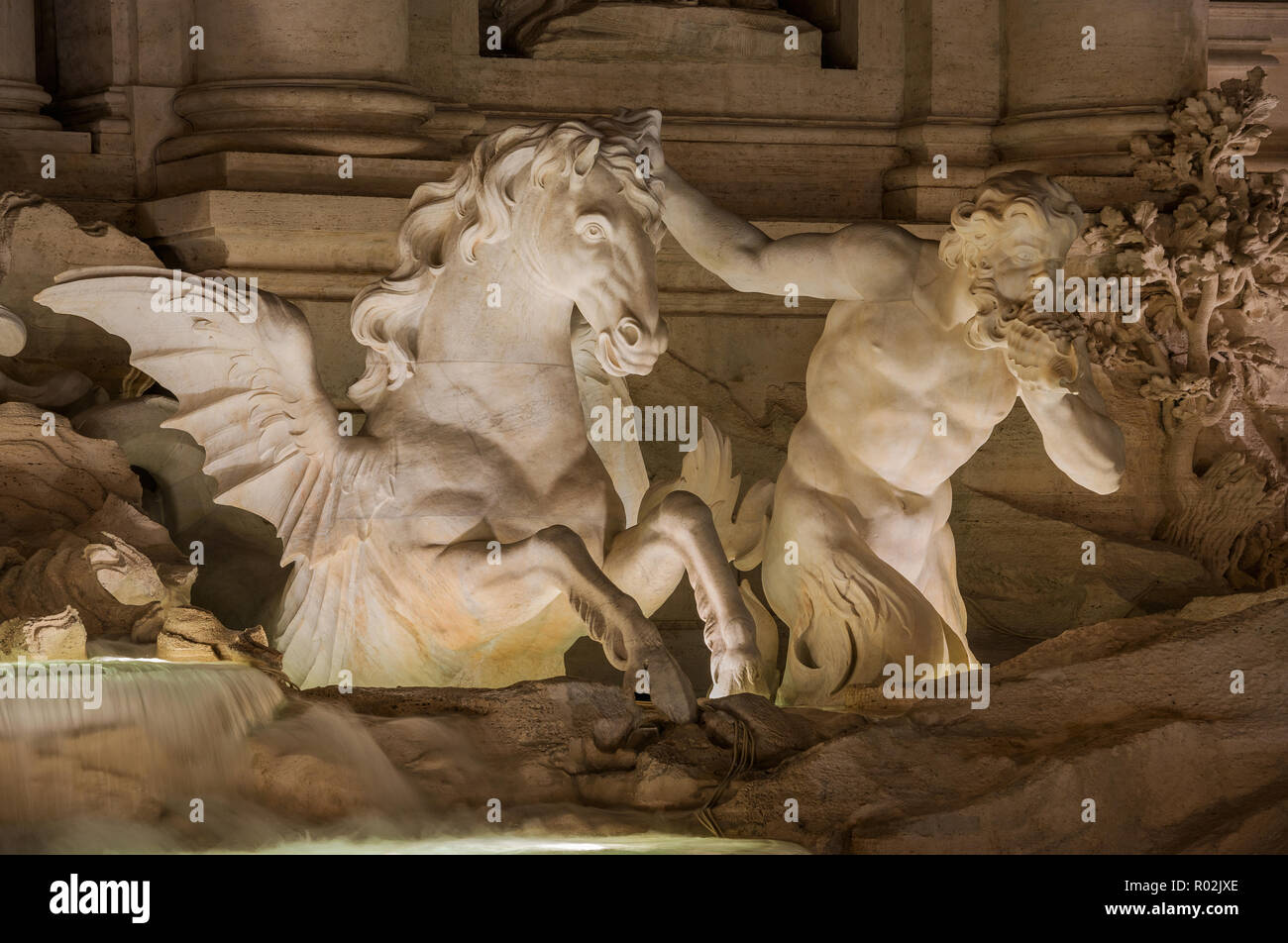 Triton mythologique dompte un hippocampe et soufflant une conque, dans la magnifique fontaine de Trévi à Rome de nuit (18e siècle) Banque D'Images