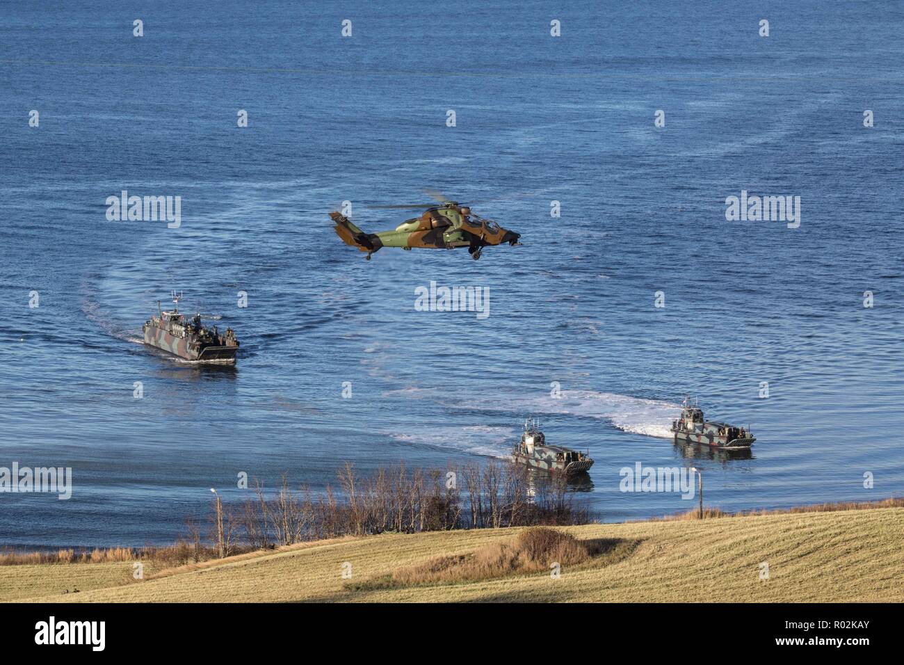 Barges de débarquement accédez au fjord de Trondheim, en Norvège, au cours de l'exercice Trident stade 18. Un hélicoptère Tigre Français le domaine des valeurs mobilières du ciel. Avec environ 50 000 membres du personnel participant à l'exercice Trident Stade 2018, c'est l'un des plus grands exercices de l'OTAN au cours des dernières années. Autour de 250 appareils, 65 navires et plus de 10 000 véhicules sont impliqués dans l'exercice en Norvège. Photo par OU-8 Sebastien Raffin / Français, une commande de l'air alliées Banque D'Images