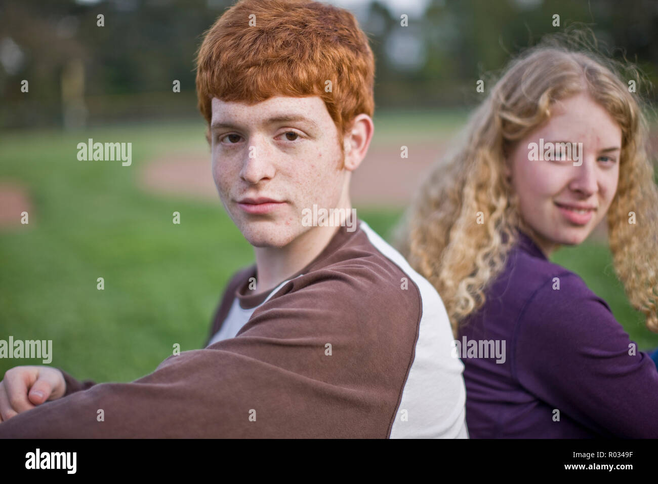 L'homme et la femme assis sur terrain de sport, smiling at the camera Banque D'Images