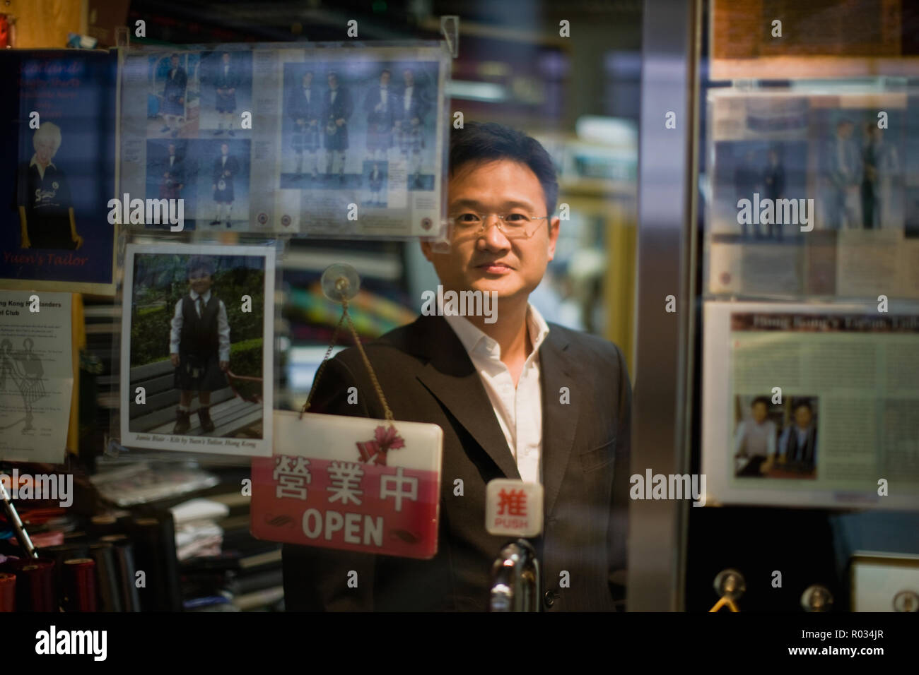 Portrait of a mid-adult man debout derrière la porte en verre d'un magasin. Banque D'Images