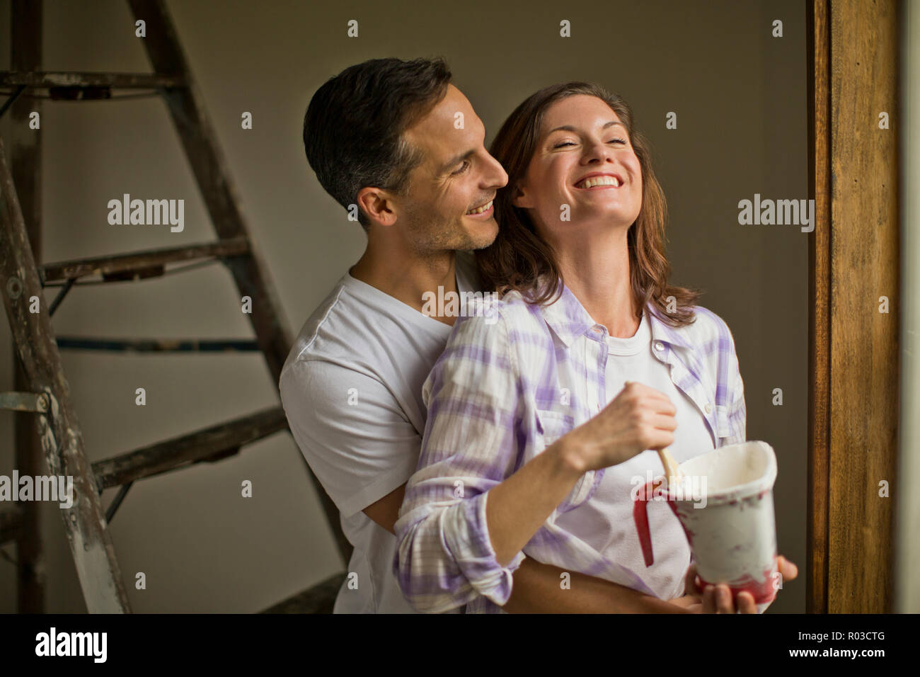 Smiling mari prend une pause et embrasse sa jolie femme pendant qu'ils rénovent leur maison et rêver à l'avenir. Banque D'Images