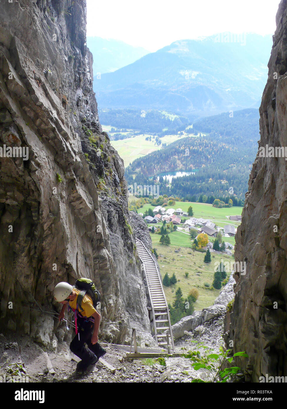 Mountain Rock climber grimpant à travers une gorge rocheuse abrupte sur son chemin à un haut sommet alpin avec une très belle vue derrière lui des Alpes Suisses Banque D'Images