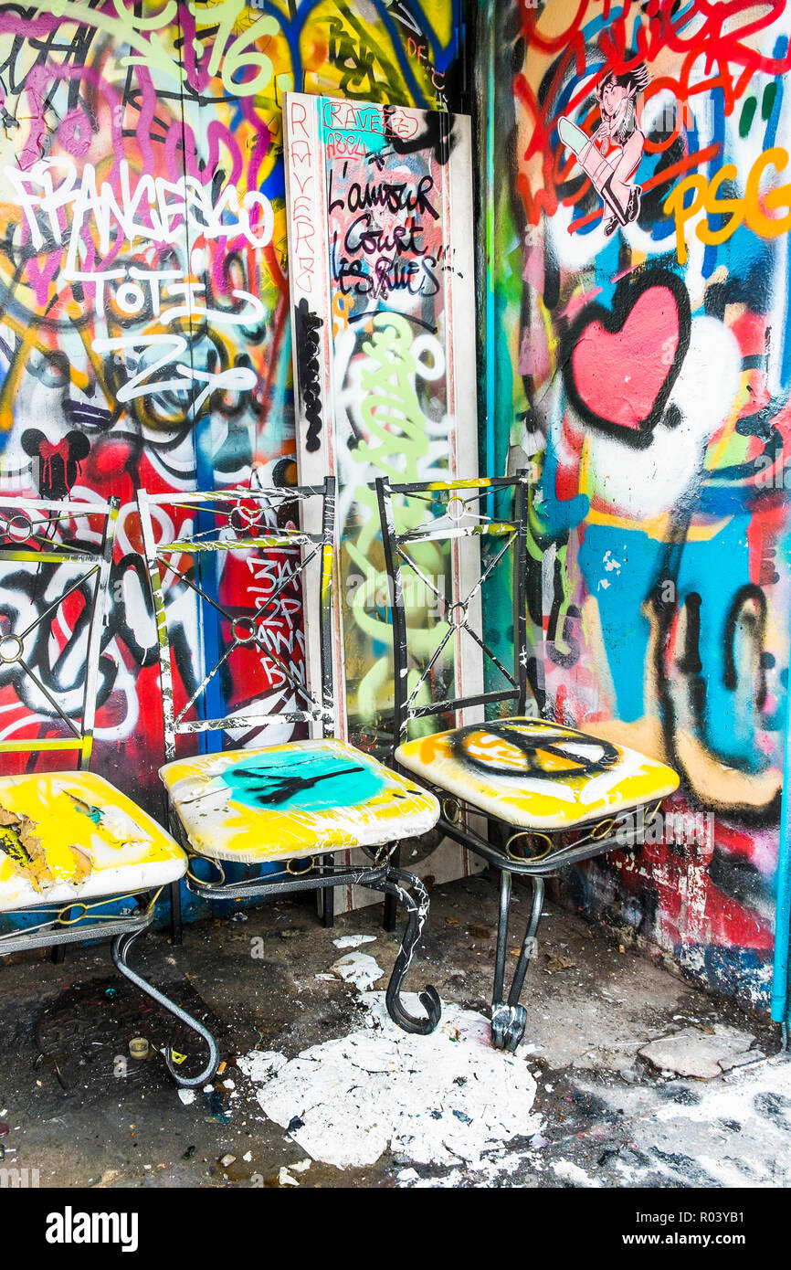 Chaises peintes en face de graffiti mur couvert Banque D'Images