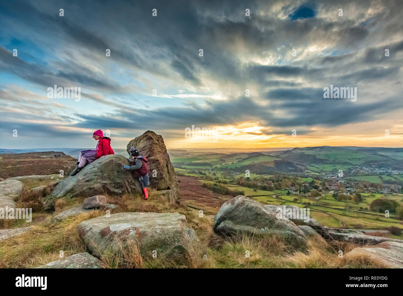 Beau paysage photographie d'enfants jouant sur les rochers coucher du soleil à Curbar Edge, parc national de Peak District, Derbyshire, Angleterre Octobre 2018 Banque D'Images