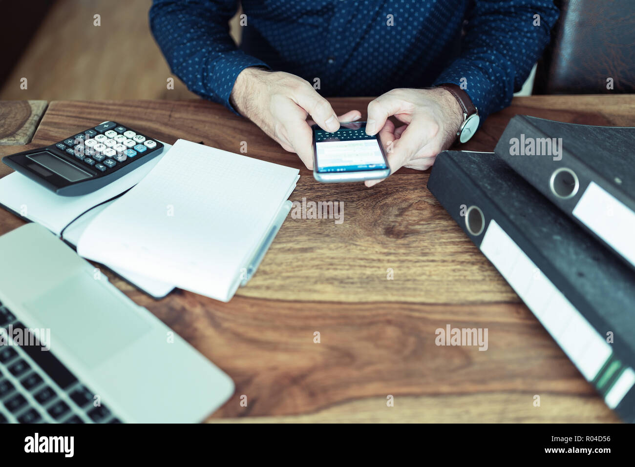 L'homme assis à table office texting on smartphone Banque D'Images