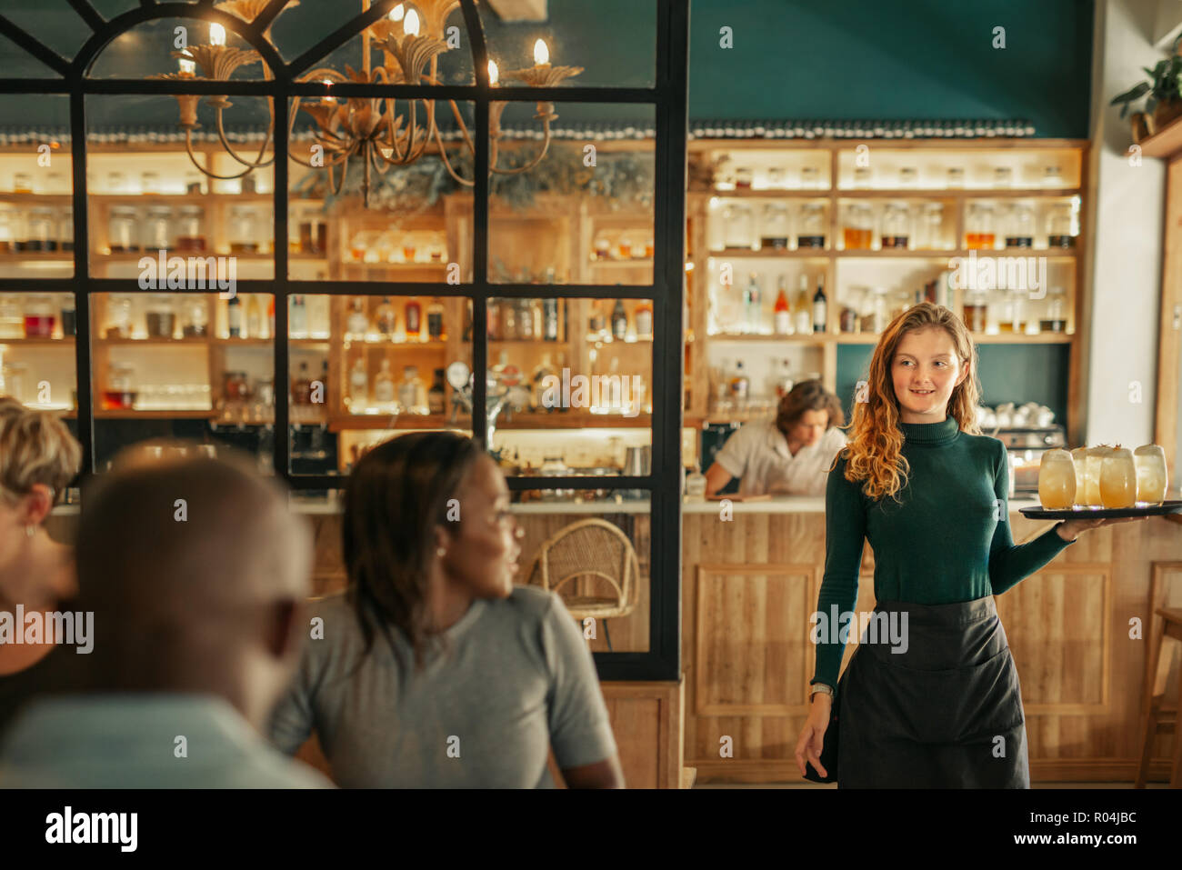 Smiling waitress apportant des boissons aux gens assis dans un bar Banque D'Images