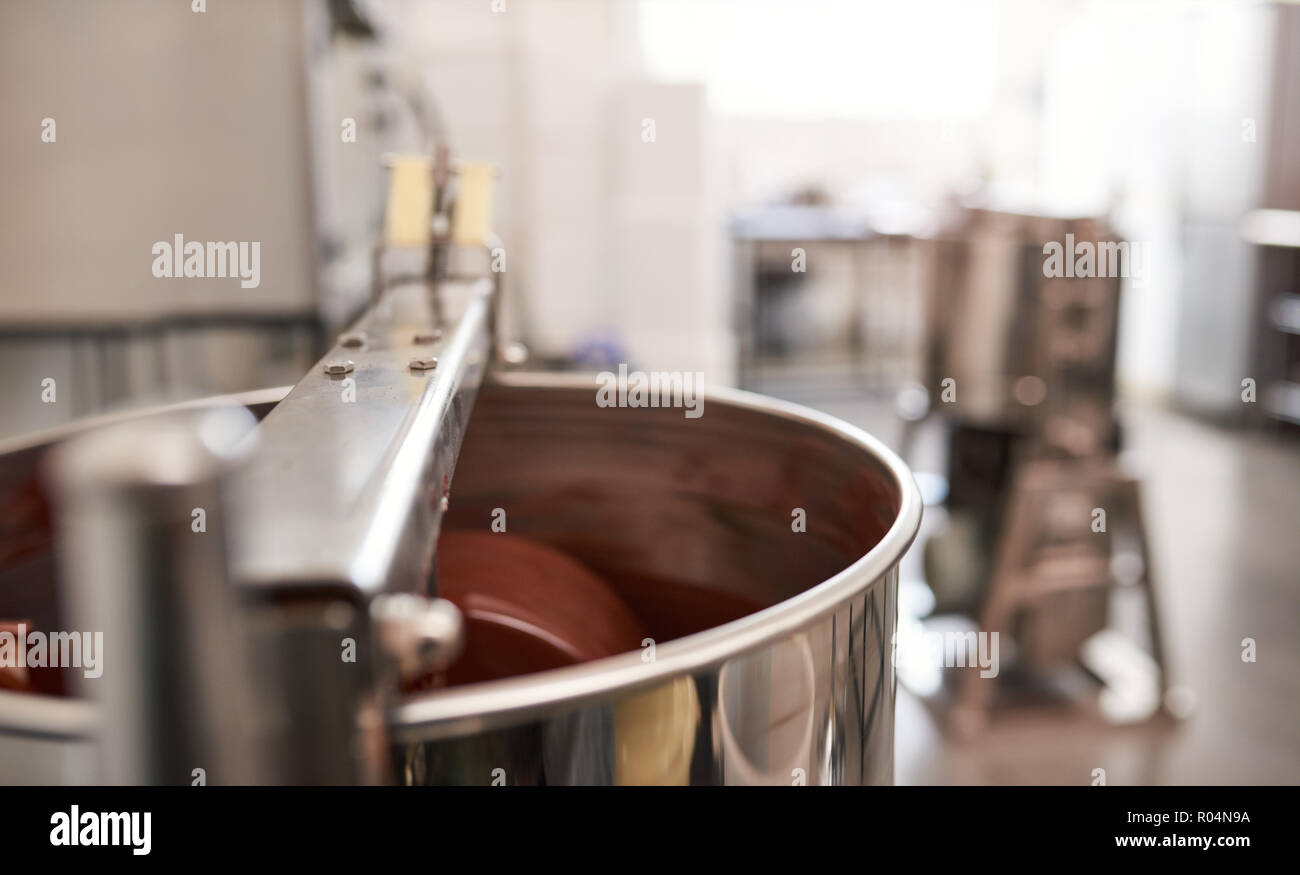 Mélangeur en acier inoxydable en remuant le chocolat fondu dans un atelier de fabrication artisanale Banque D'Images