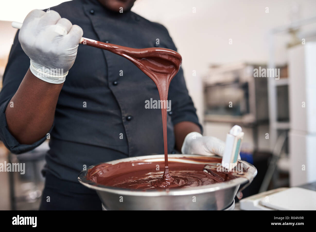 Le chocolat fondu en remuant travailleur dans un bol en acier inoxydable Banque D'Images