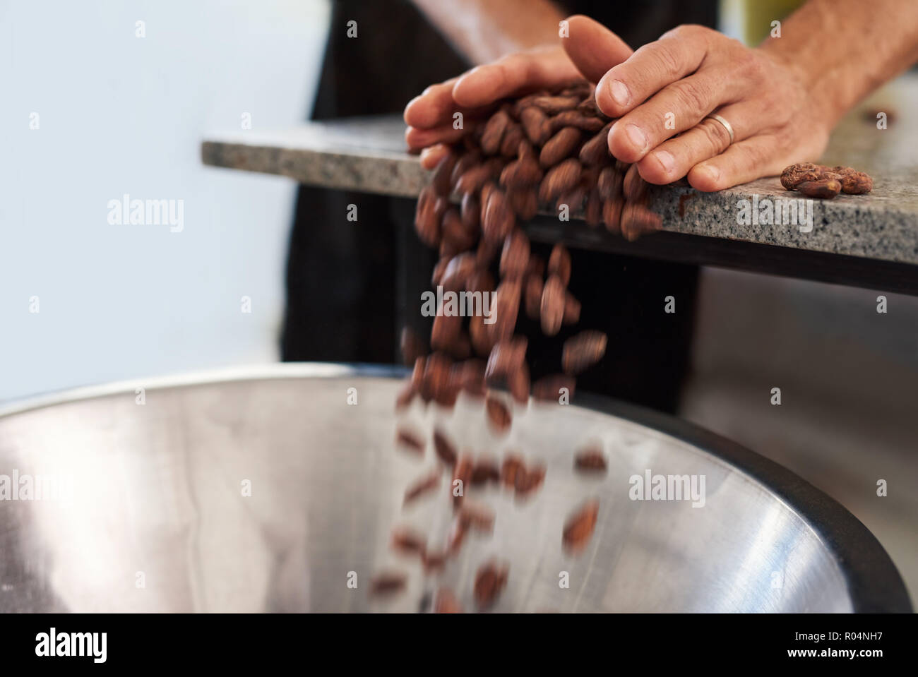 Versant travailleur les fèves de cacao dans un bol pour la production de chocolat Banque D'Images