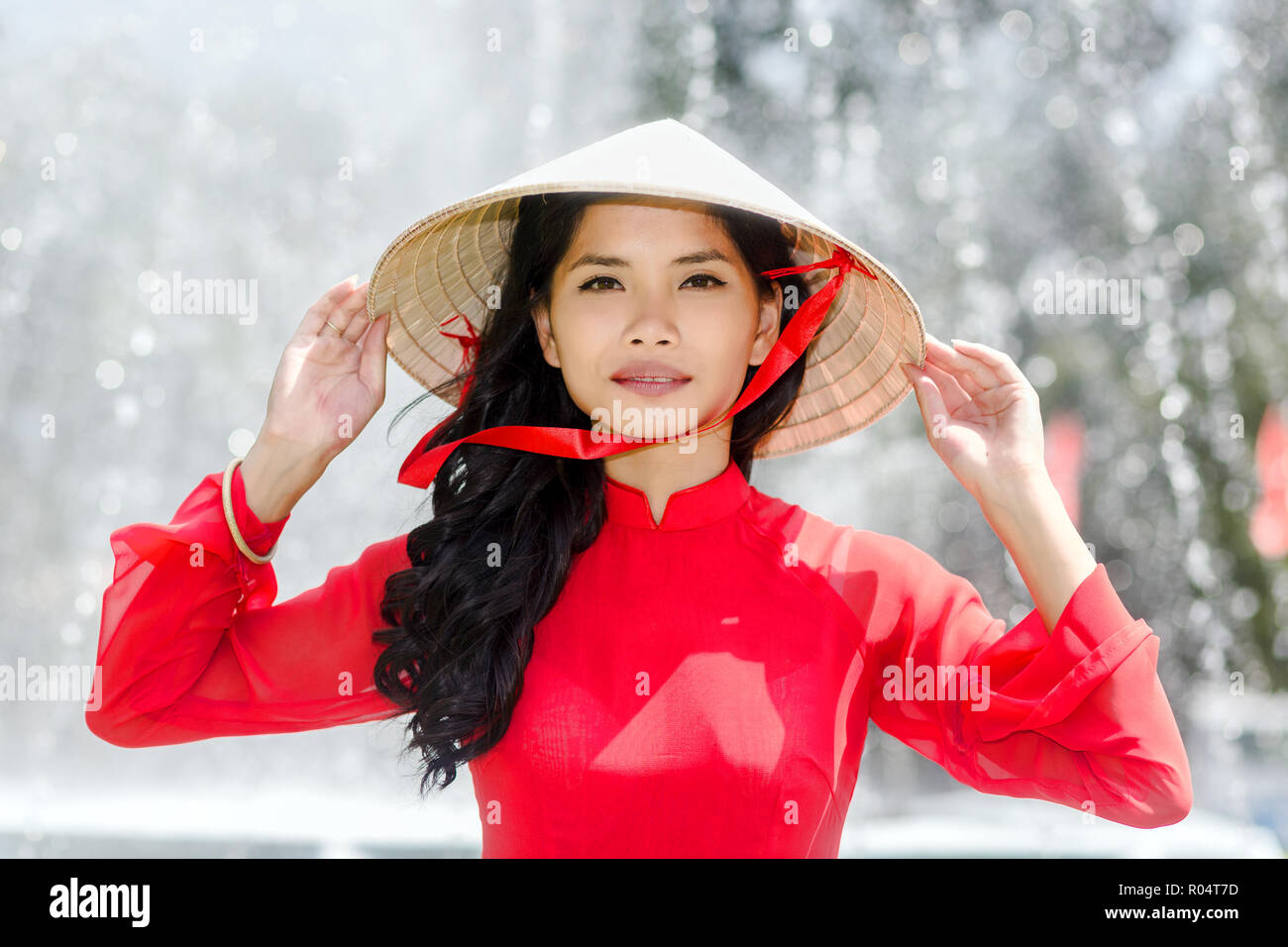 Vietnamienne dans un costume rouge et chapeau conique debout devant une  fontaine Photo Stock - Alamy