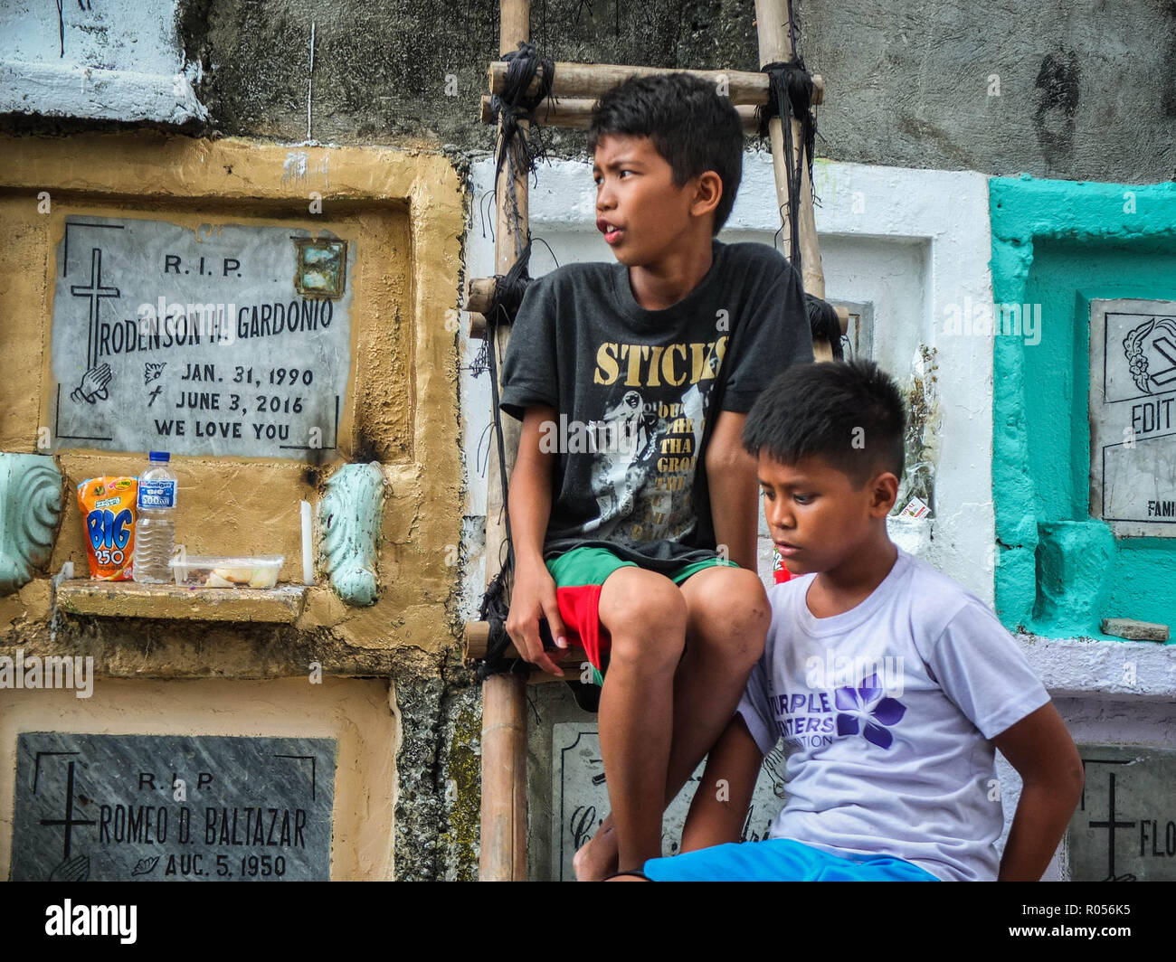 Manille, Philippines. 1er novembre 2018. Les jeunes garçons en attente de clients, leur activité était d'allumer des bougies, mettre des fleurs, ou d'aider leur client à traverser de l'autre côté du cimetière locaux par l'utilisation de leur échelle de bambou.Des millions de Philippins troupeau aux cimetières à travers le pays pour rendre visite à leurs défunts amoureux. Payer leurs respects à des êtres chers qui sont morts. C'est la tradition et la culture philippine. Credit : Josefiel Rivera SOPA/Images/ZUMA/Alamy Fil Live News Banque D'Images