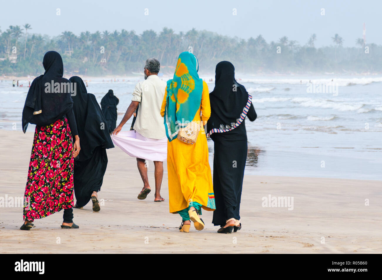 Les femmes musulmanes à pied le long de la plage, un homme marche devant. Vue depuis l'arrière. Le Sri Lanka. Banque D'Images