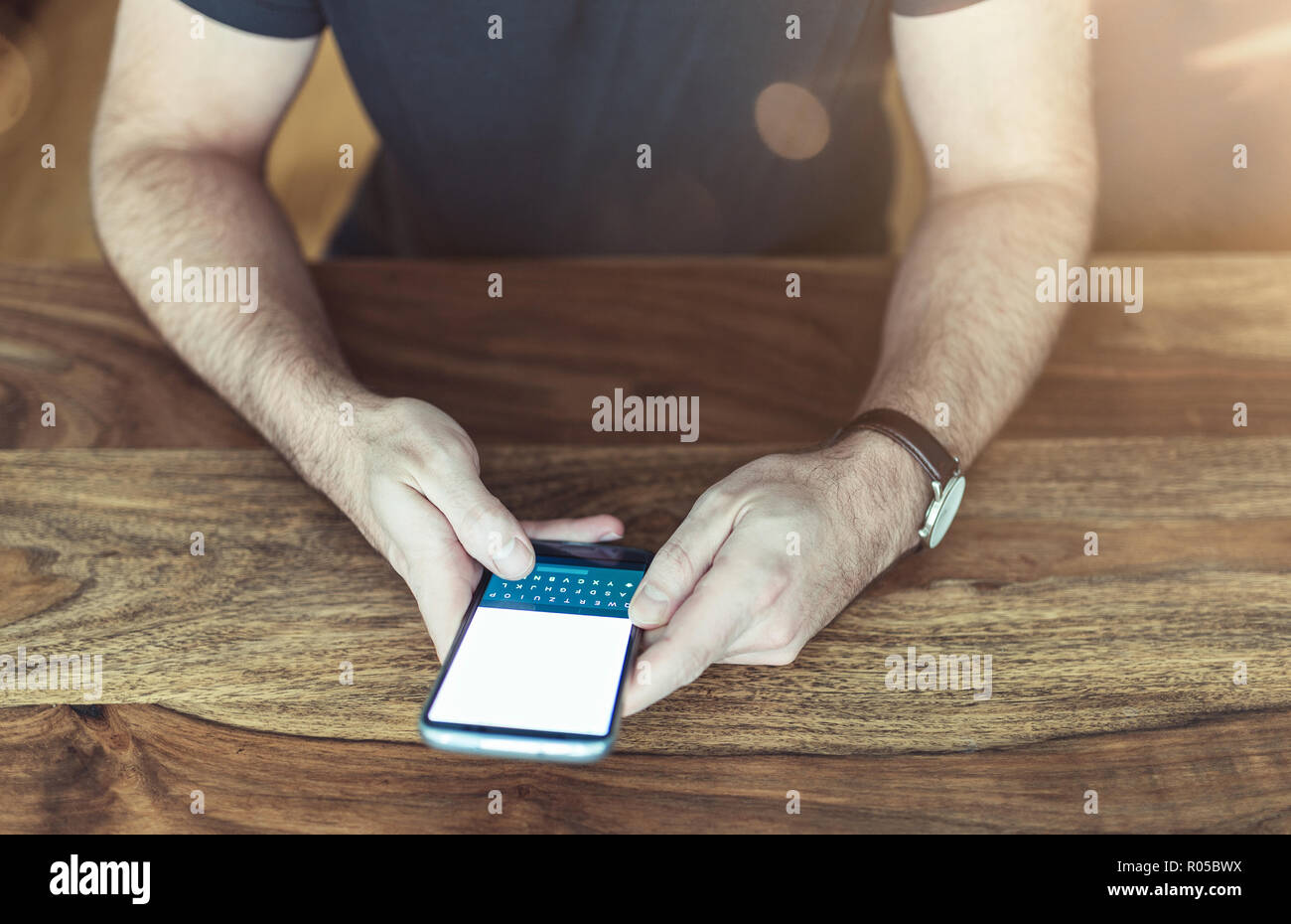 L'homme assis à table à l'aide d'un smartphone Banque D'Images