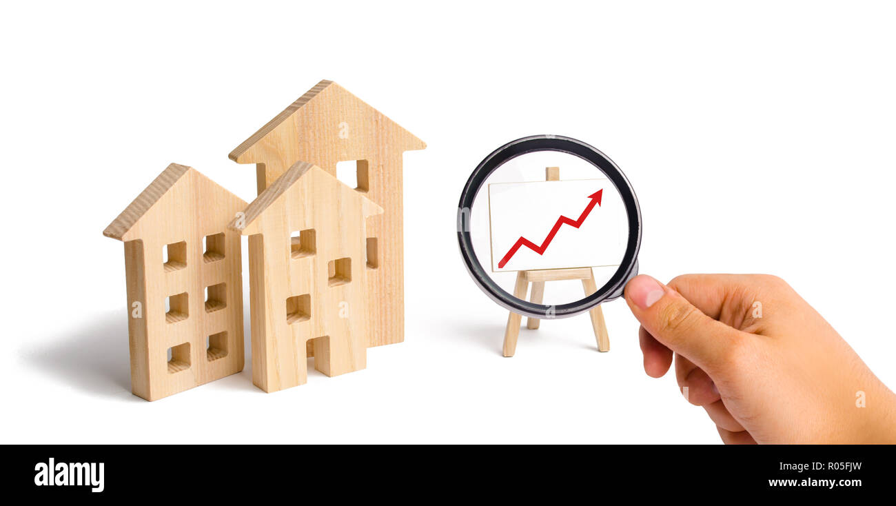 Loupe à la recherche à la maisons en bois stand avec flèche rouge vers le haut. Demande croissante de logements et l'immobilier. La croissance de la ville et de ses p Banque D'Images