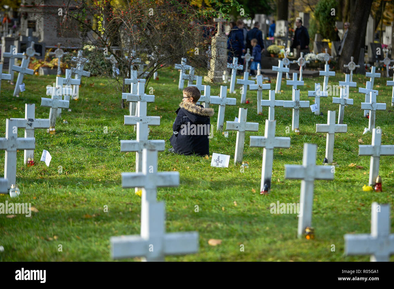 Un enfant vu accroupis à côté de tombes militaires les soldats inconnus au Cimetière militaire pendant la célébration. Toussaint, également connu comme le Jour des Morts, est un Catholique journée du souvenir pour les amis et les êtres chers qui sont décédés. Banque D'Images