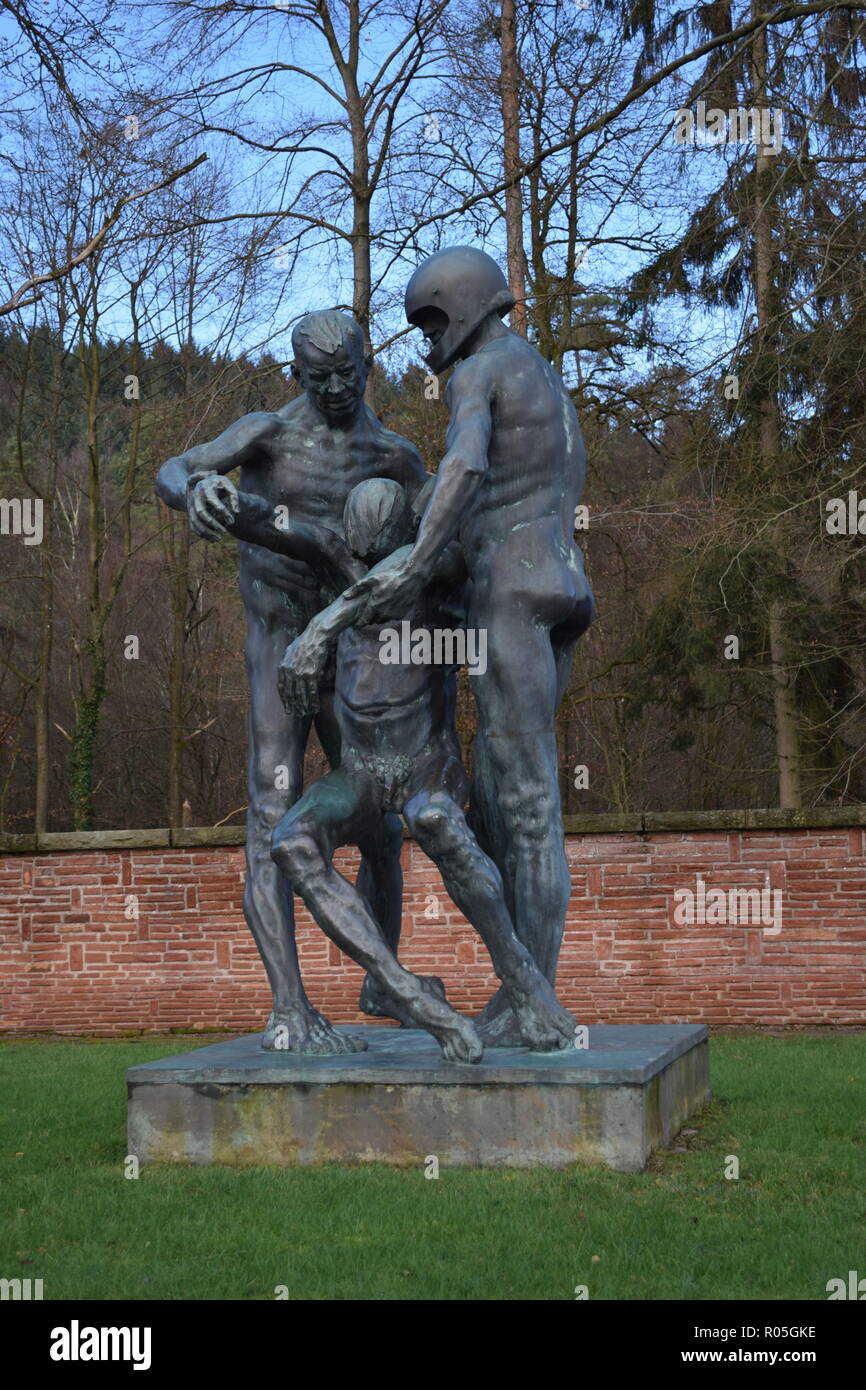 Une statue de bronze dans le cadre de ciel bleu en hiver, dans un cimetière de guerre représente deux hommes portant un blessé victime mortelle comme un symbole de l'impuissance. Banque D'Images
