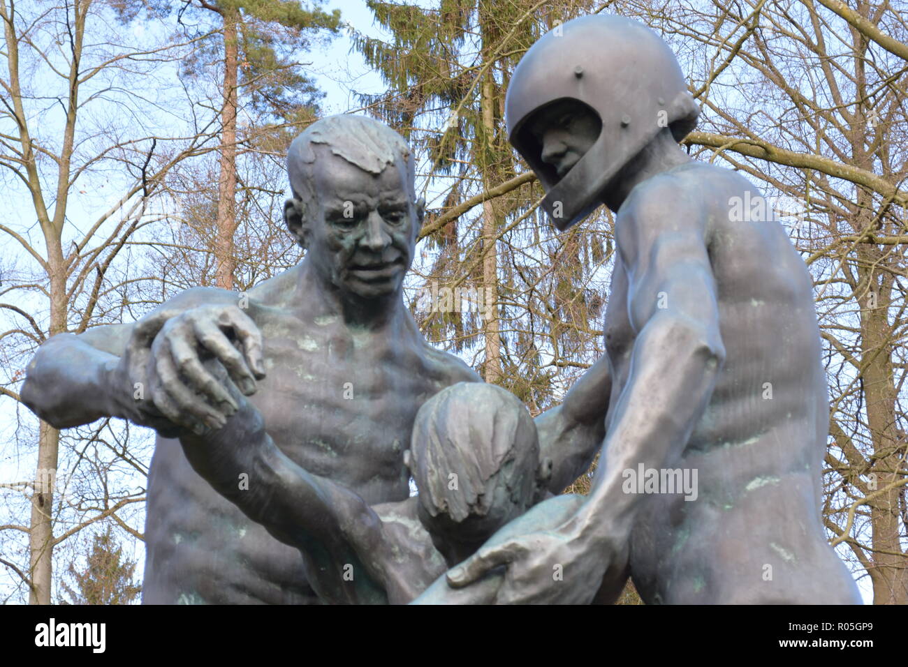 Une statue de bronze dans le cadre de ciel bleu en hiver, dans un cimetière de guerre représente deux hommes portant un blessé victime mortelle comme un symbole de l'impuissance. Banque D'Images