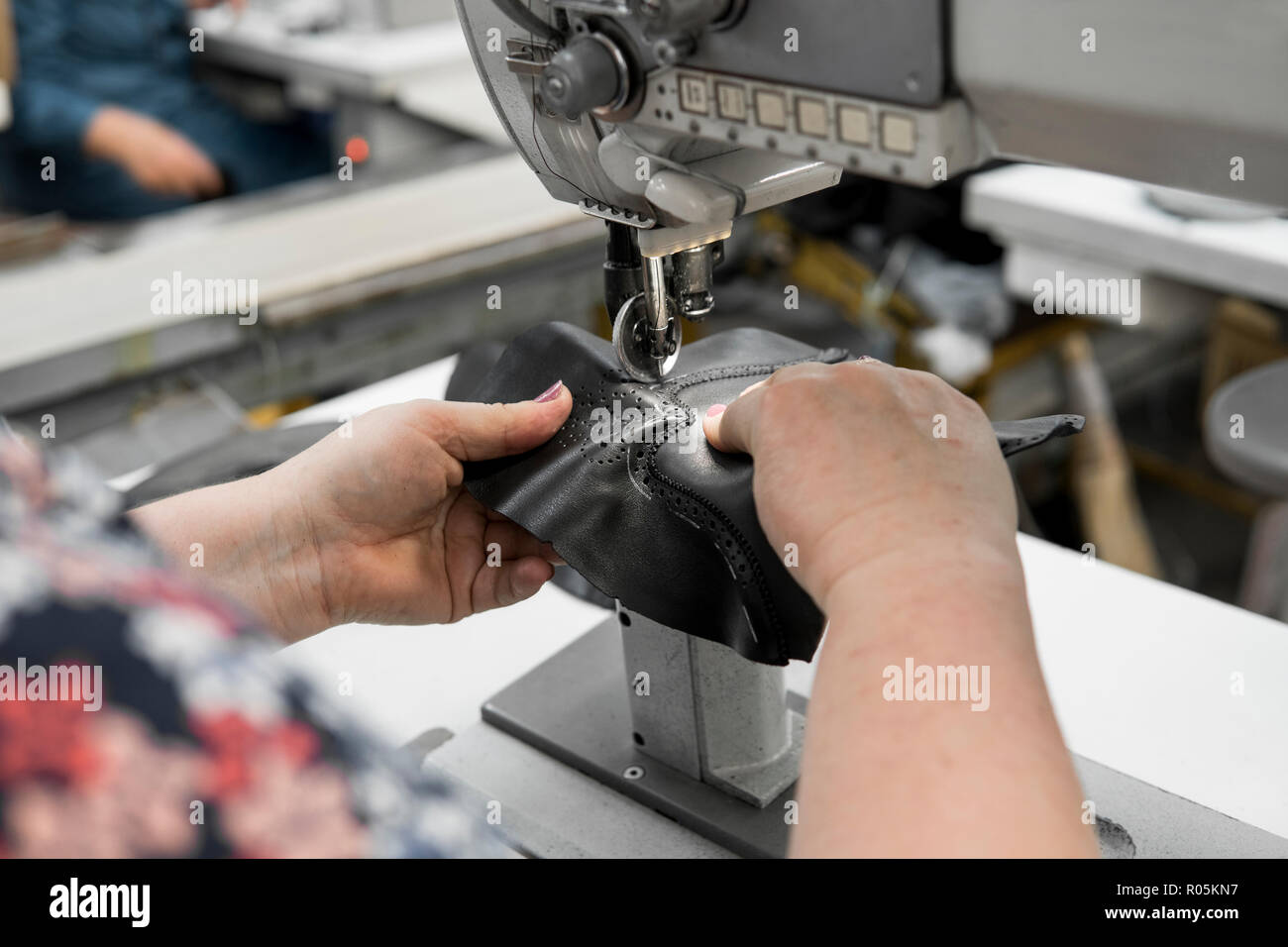 Machine à coudre dans un atelier de cuir en action avec les mains sur un  travail pour des détails en cuir chaussures. Old Women's Hands avec machine  à coudre à la fabrique