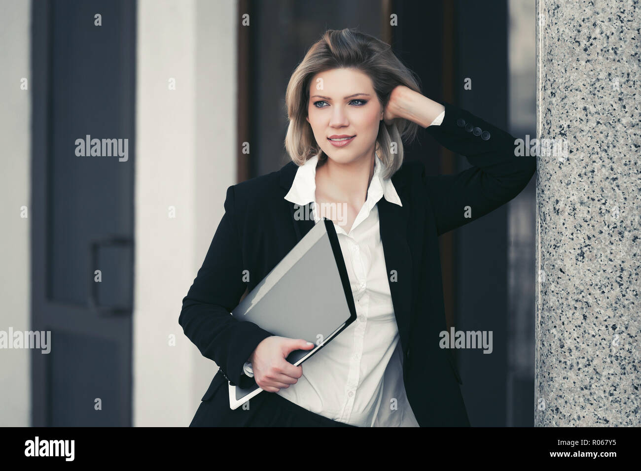 Happy young business woman avec un dossier d'un immeuble de bureaux. Modèle de mode Élégant blazer noir en piscine Banque D'Images