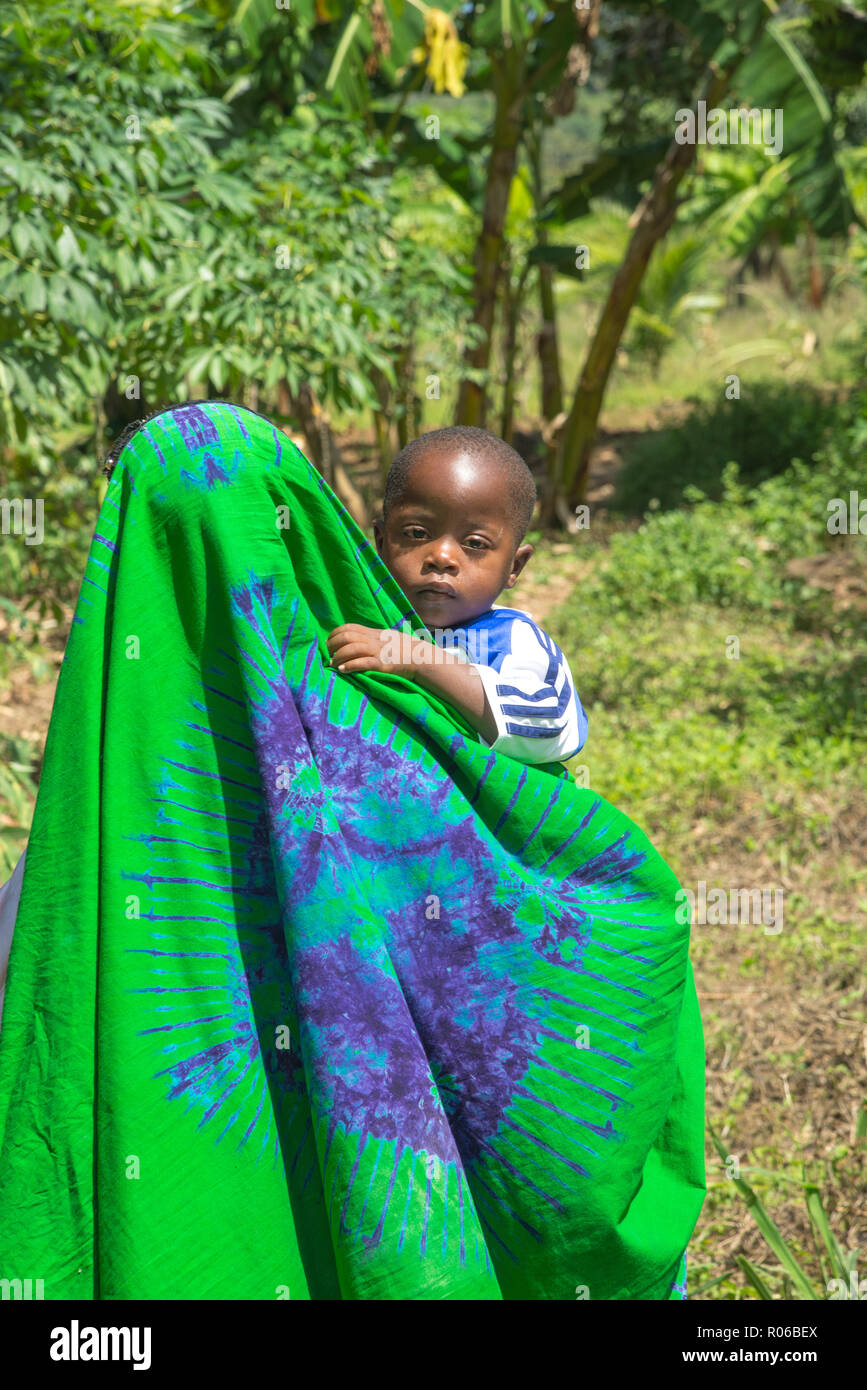 Mère en robe colorée tenant un enfant sur le bras au Kenya, Afrique Banque D'Images