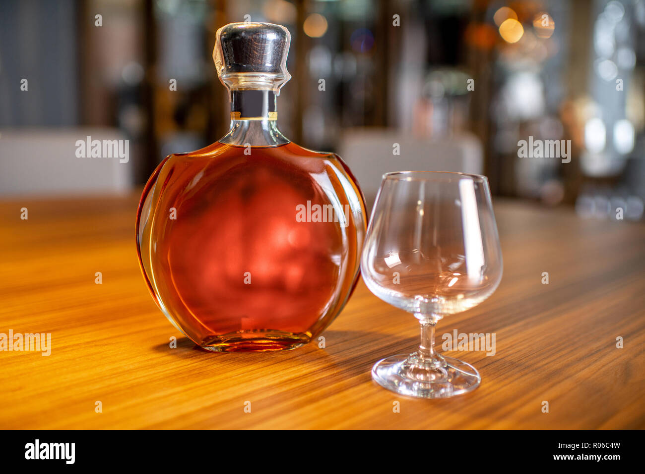 Bouteille de cognac avec le verre vide sur la table de salon à cigares Banque D'Images