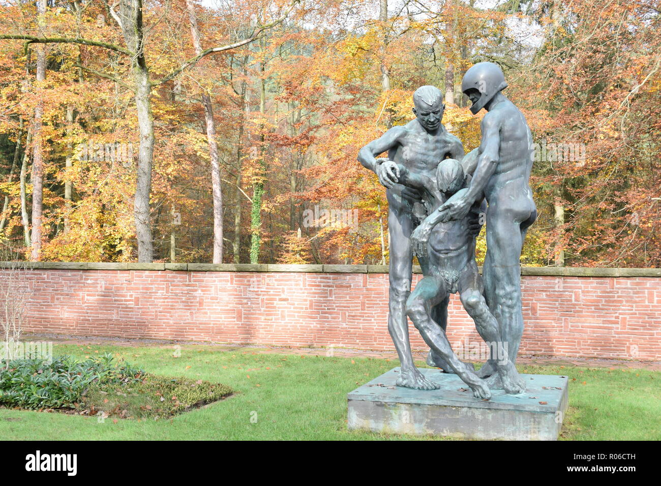 Une statue de bronze à l'automne dans le cimetière de guerre Reimsbach représente deux hommes portant un blessé victime mortelle comme un symbole de l'impuissance de l'homme. Banque D'Images