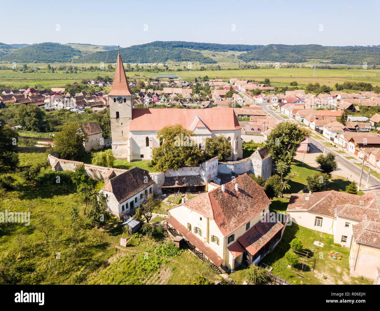 Saros pe Tarnave, église fortifiée, Transylvanie, Roumanie. Château médiéval sur une colline avec une spire, murs, toits de tuiles rouges, entourée d'un village. Banque D'Images